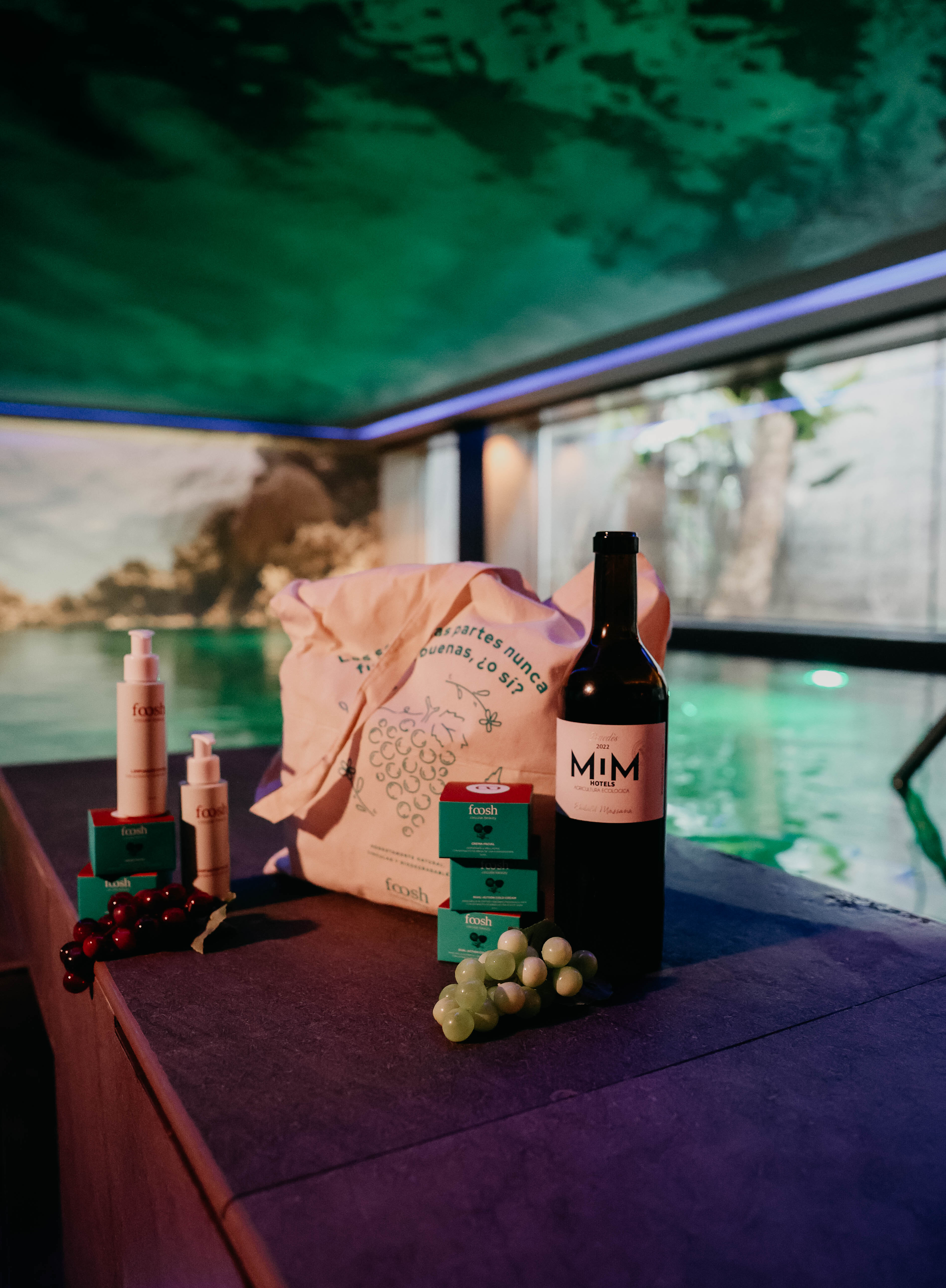 Organic Foosh skincare, MIM wine, tote bag, grapes beside a glowing pool.