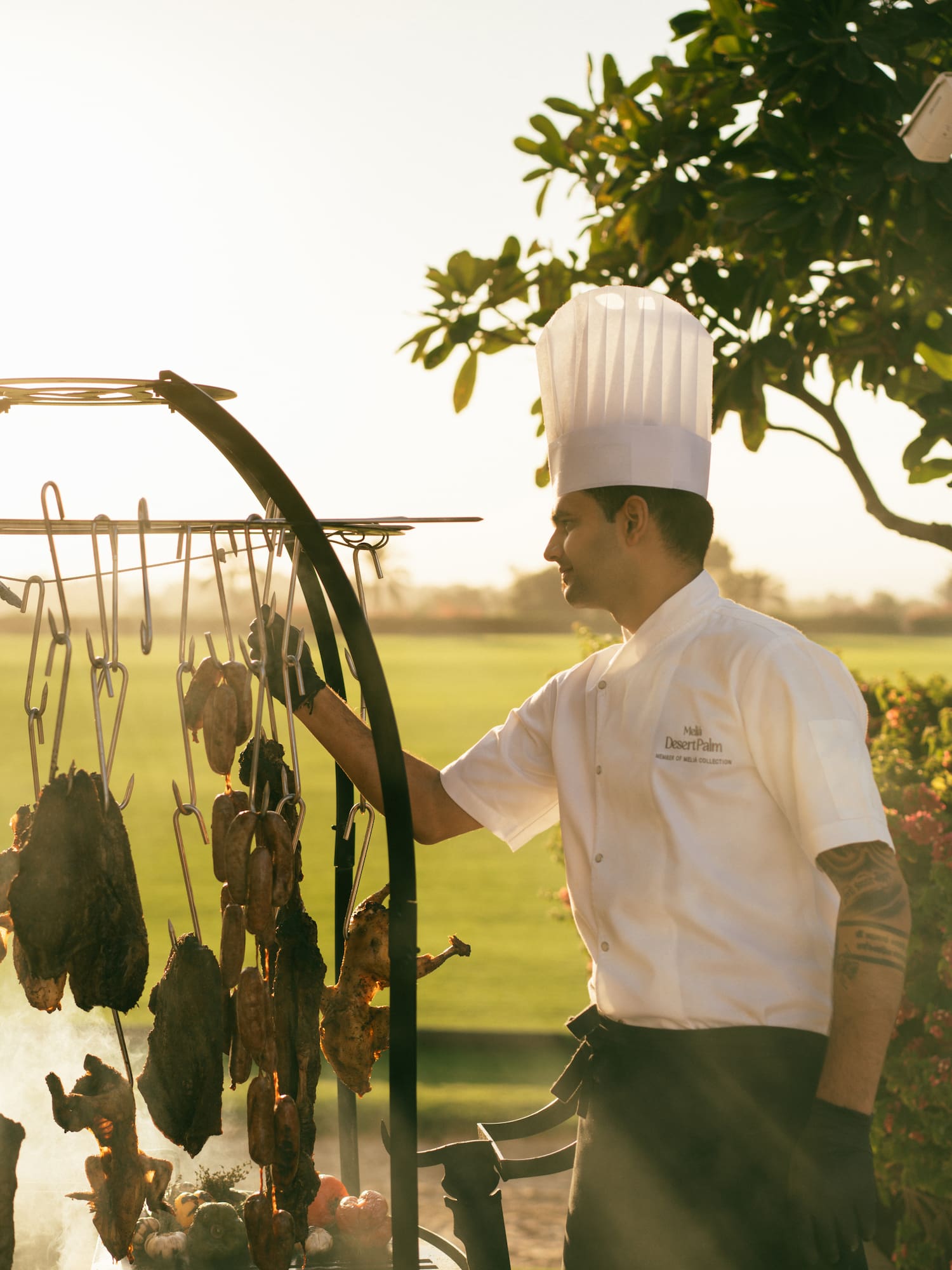 Chef cooking on the asado grill, with view of the polo field