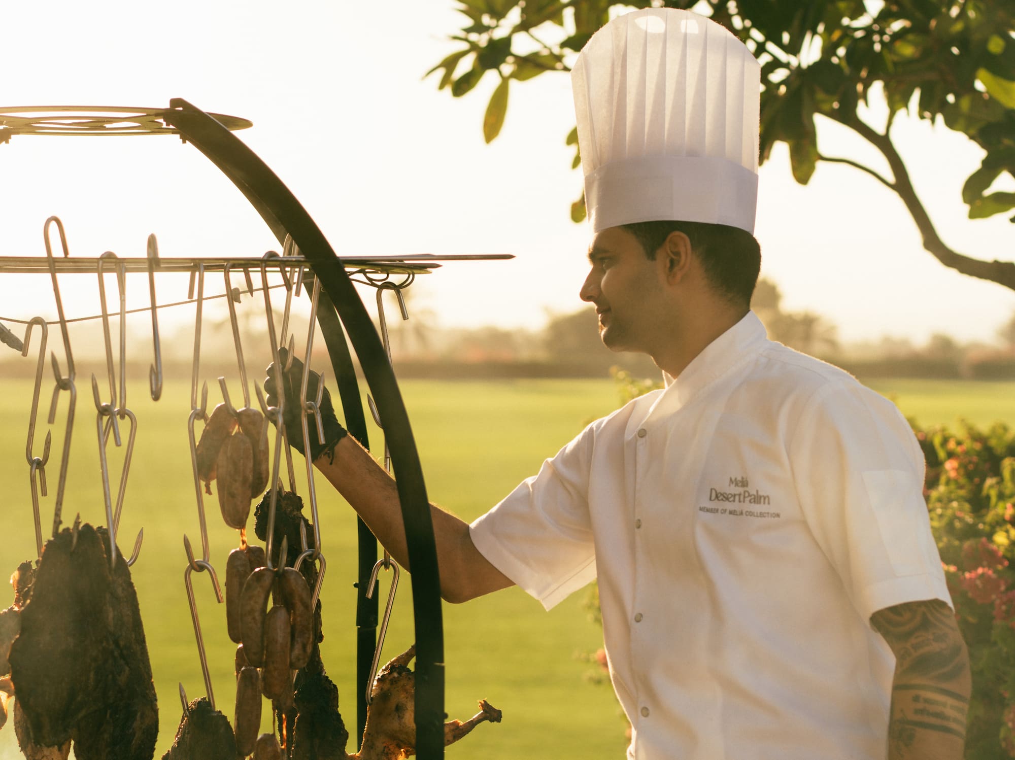Chef cooking on the asado grill, with view of the polo field