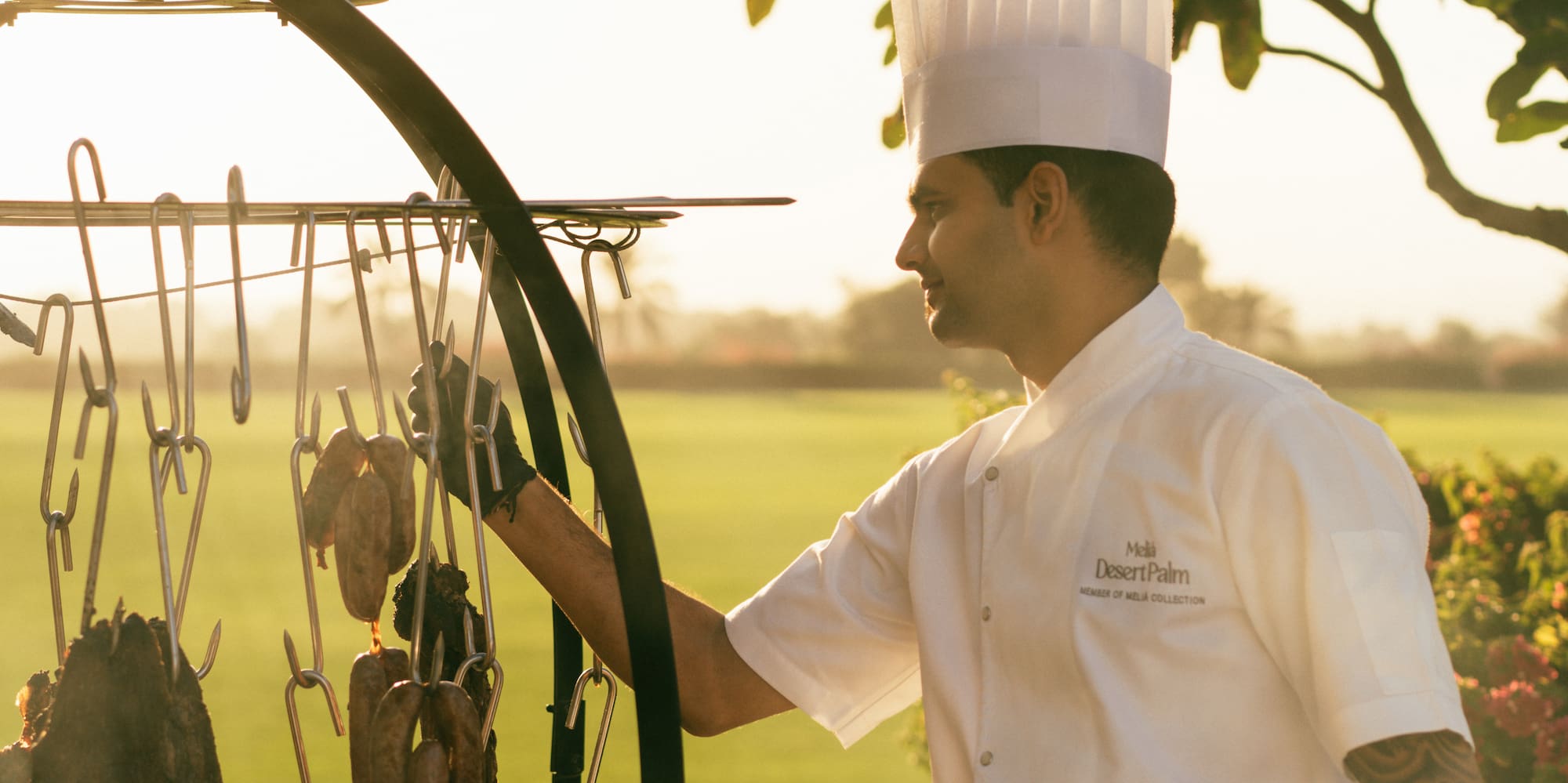 Chef cooking on the asado grill, with view of the polo field