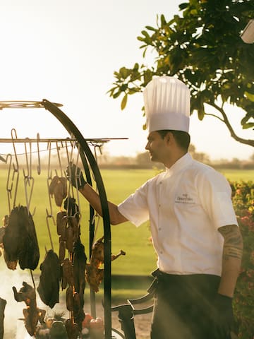 Chef cooking on the asado grill, with view of the polo field