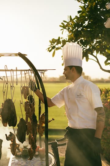 Chef cooking on the asado grill, with view of the polo field