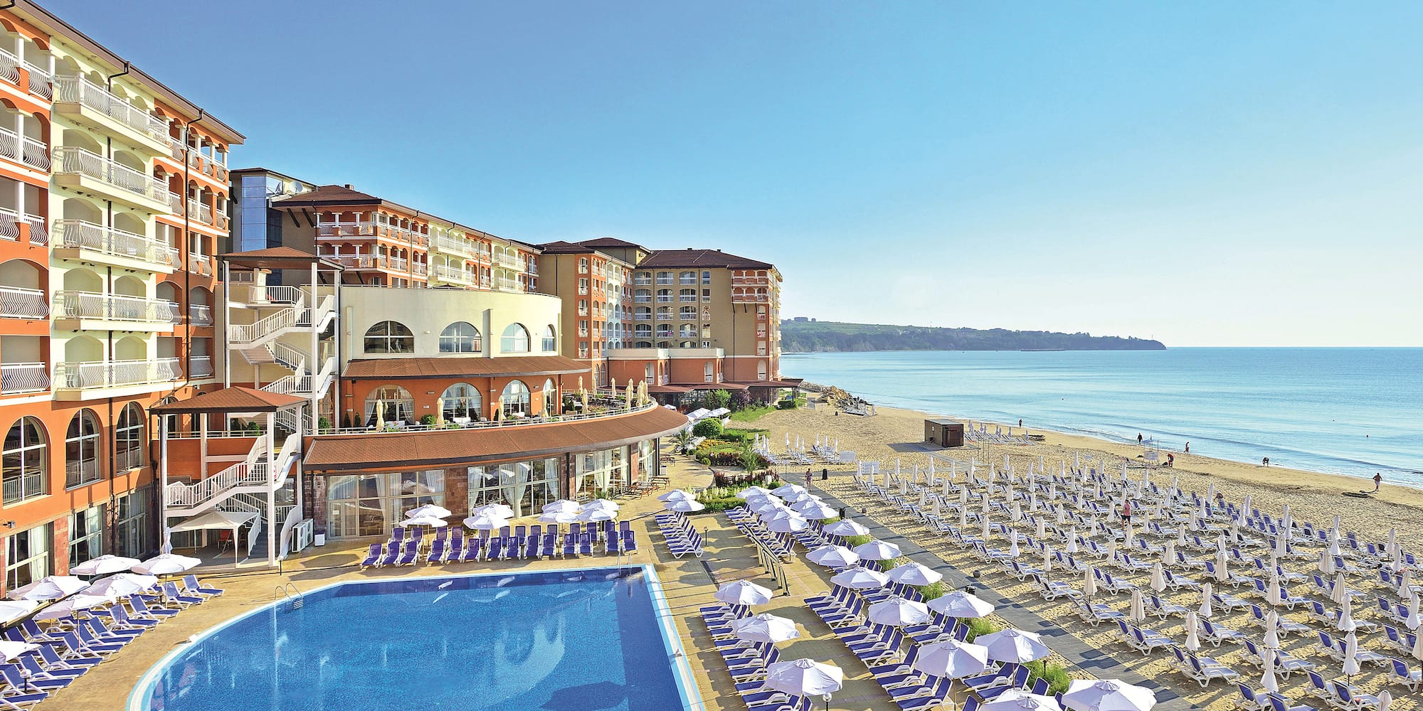 a swimming pool and a building with a beach and blue water