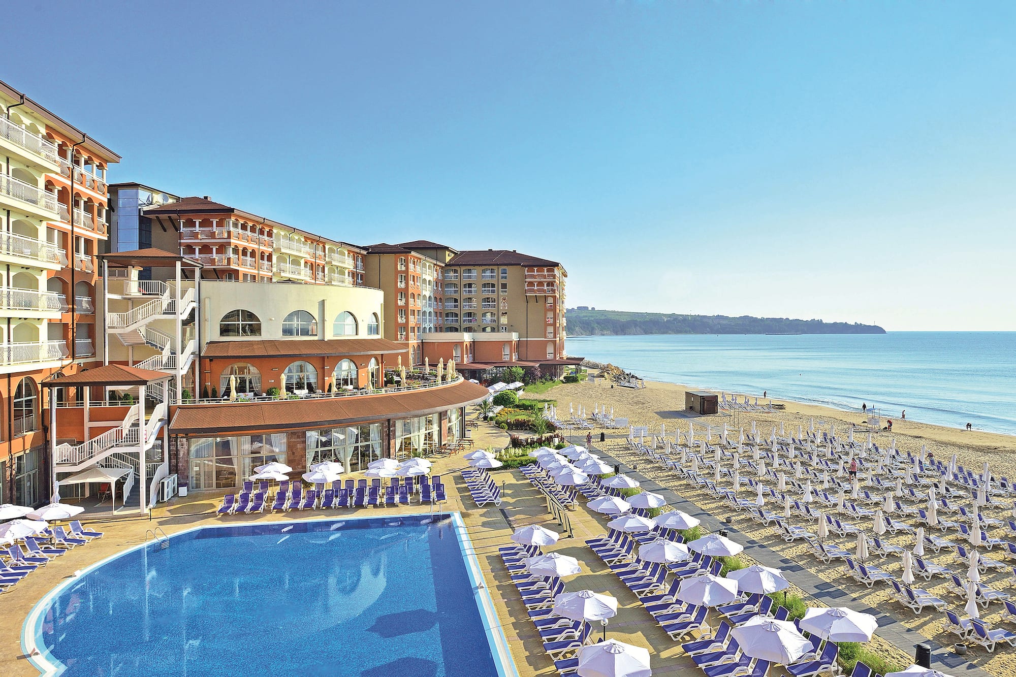 a swimming pool and a building with a beach and blue water