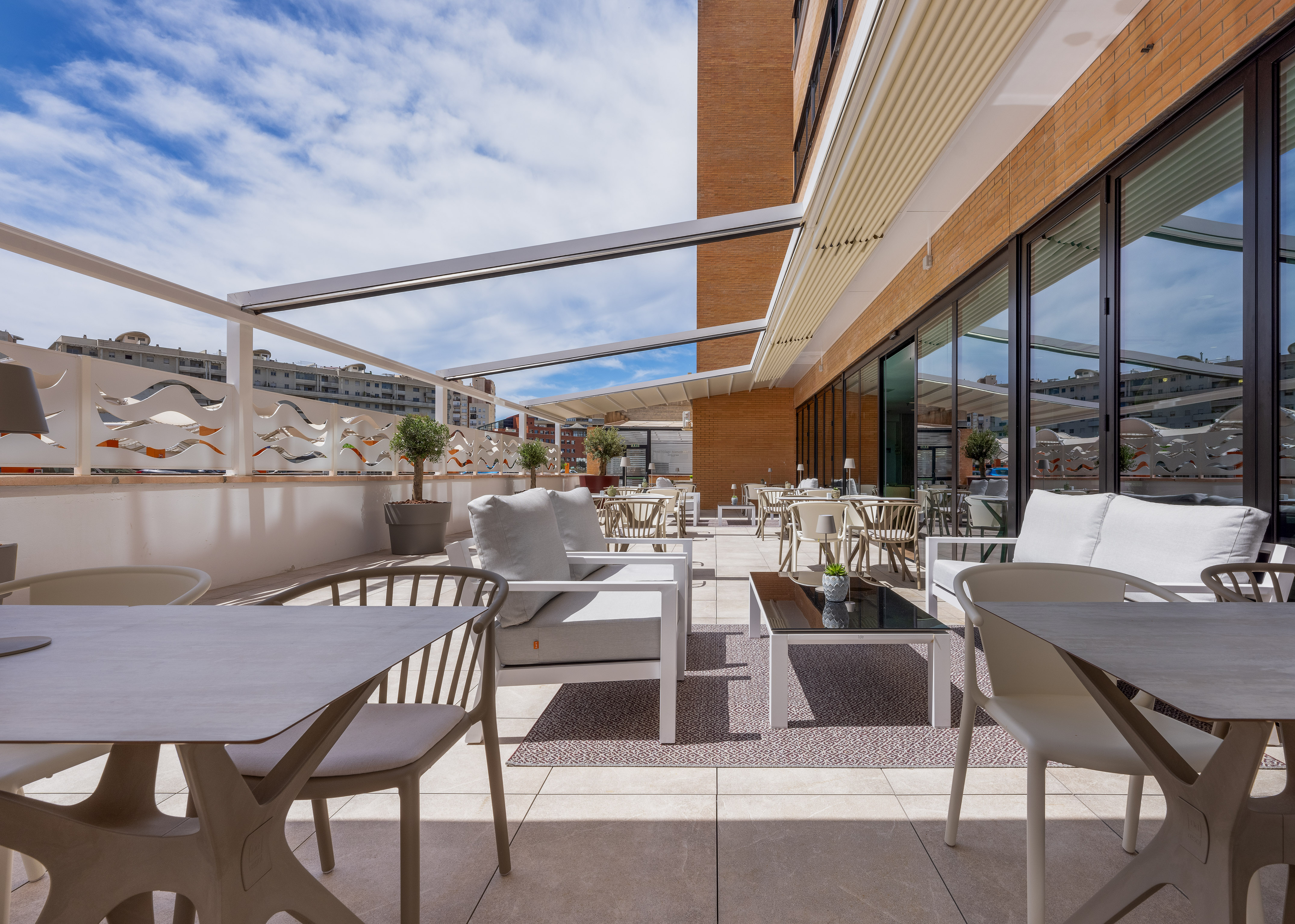 Modern outdoor patio with dining and lounge furniture, retractable roof.