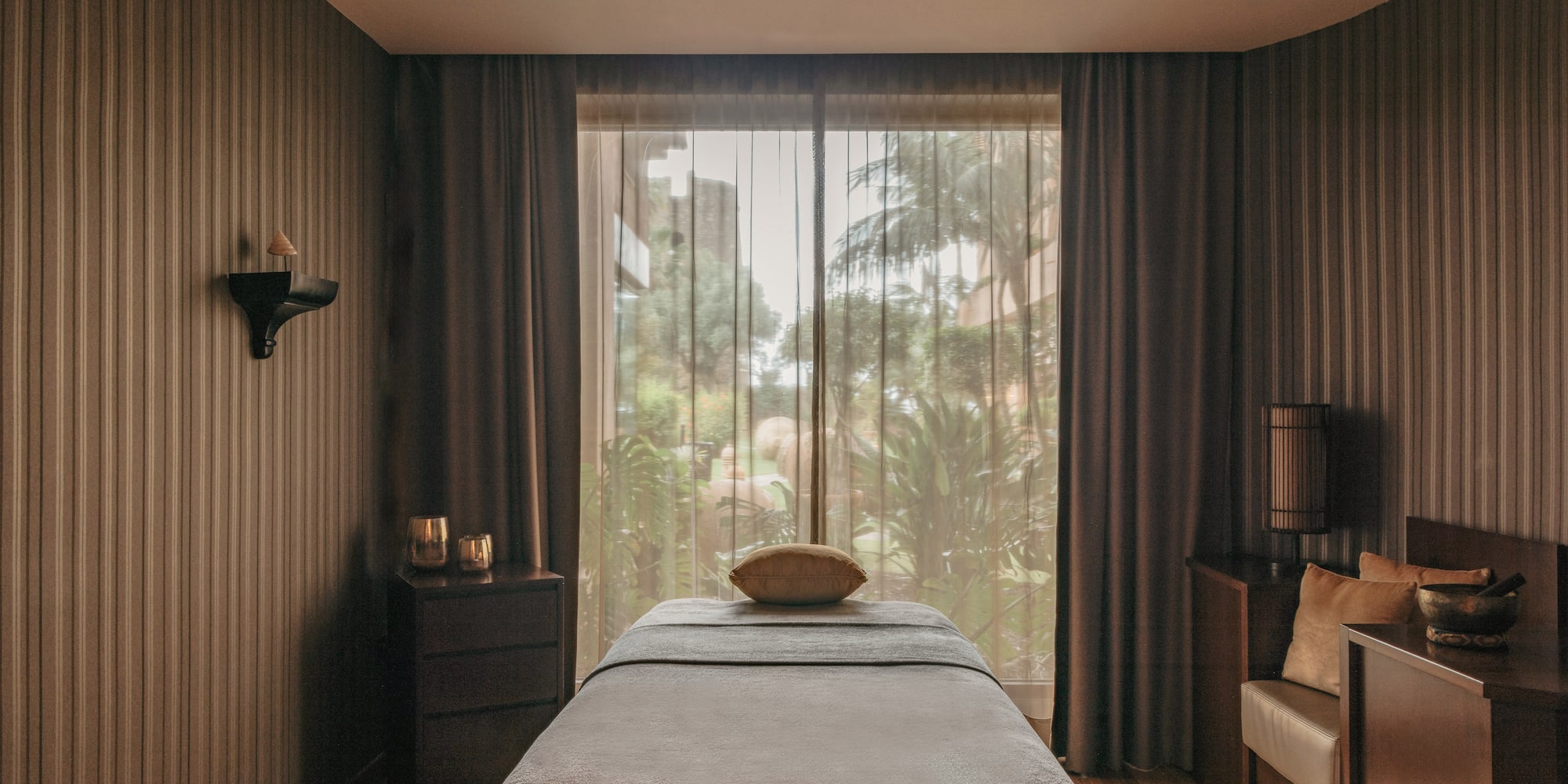 Luxurious spa treatment room with massage table and lush outdoor view.