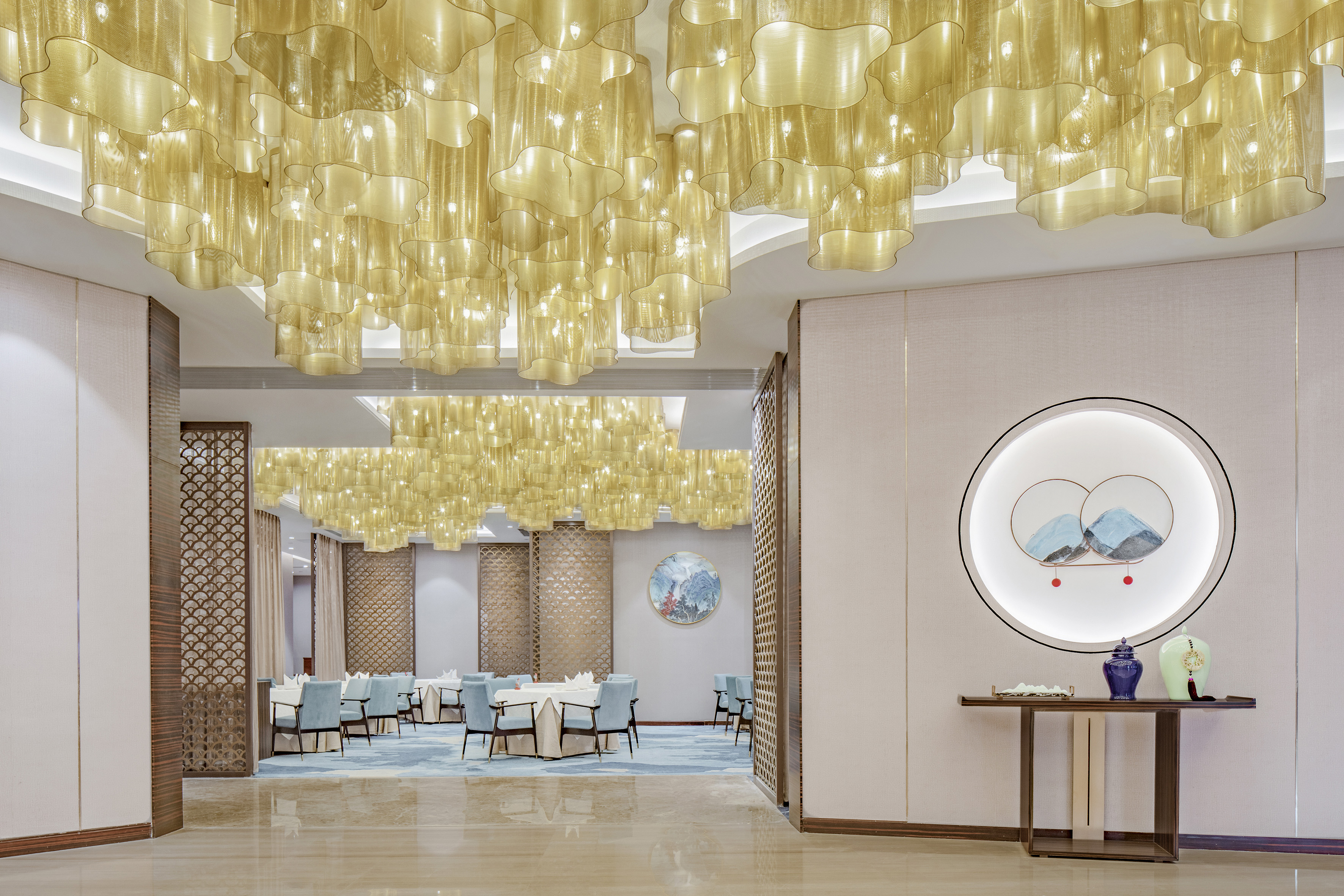 Elegant restaurant interior with unique golden chandeliers and blue dining chairs.