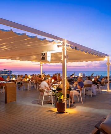 a group of people sitting at tables on a deck