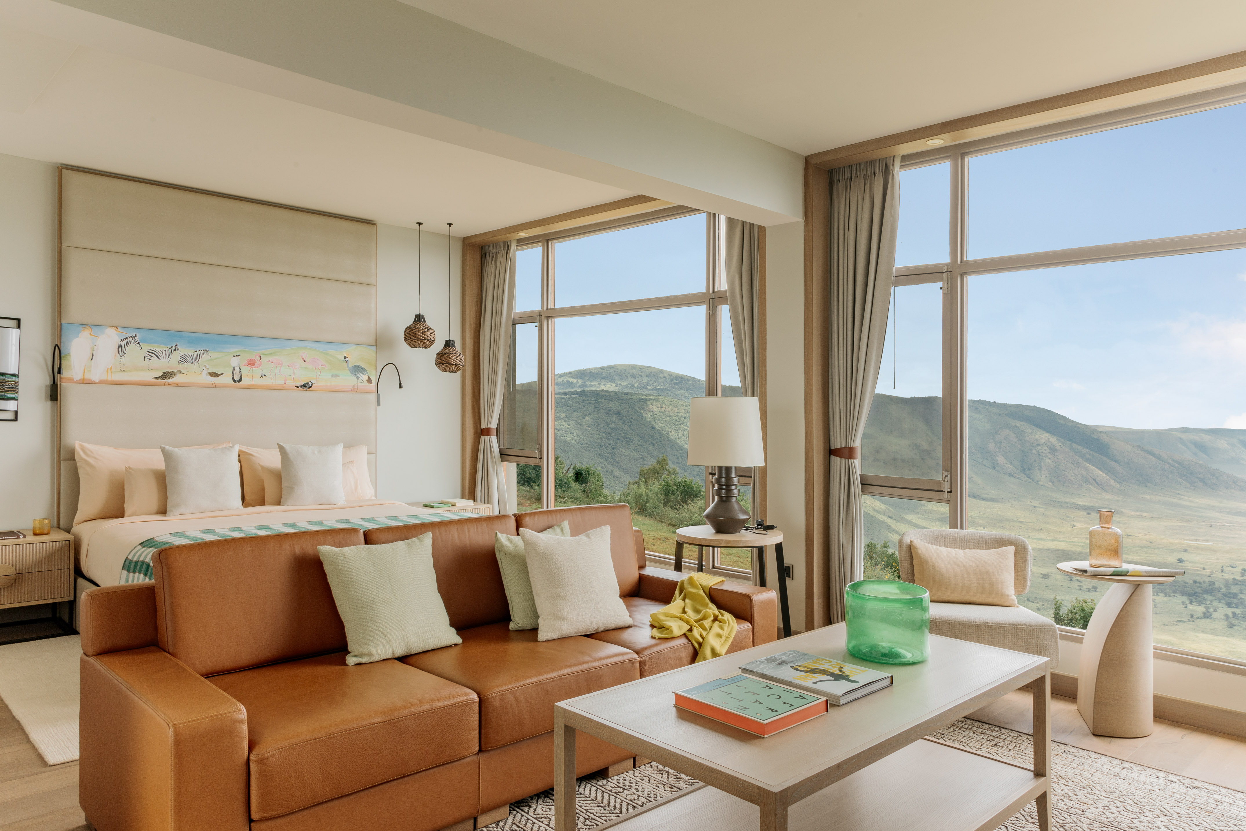 Luxury safari suite with mountain views, leather sofa, bed, and wildlife art.