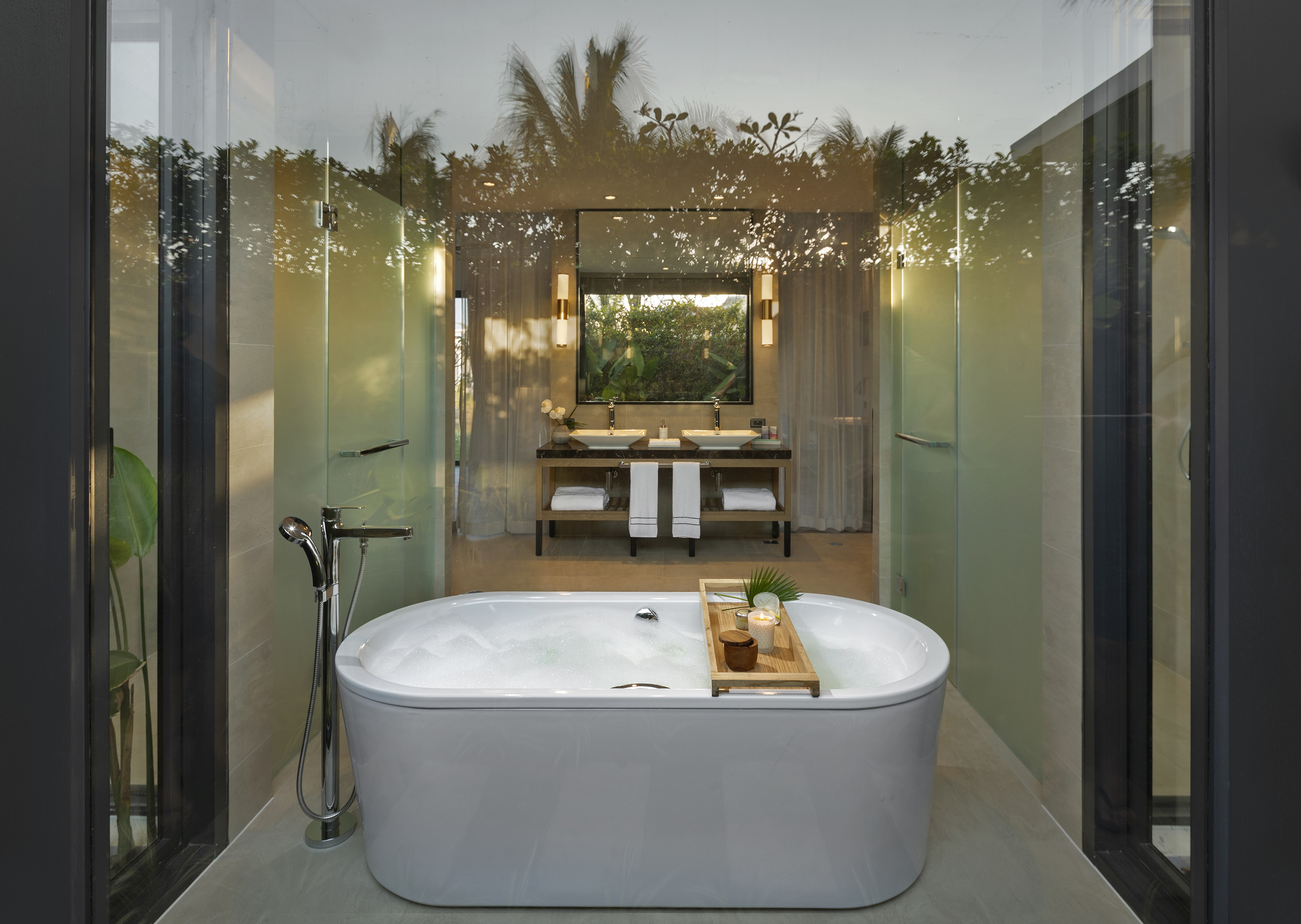 Luxurious modern bathroom with bubble-filled bathtub, double vanity, and tropical reflections.