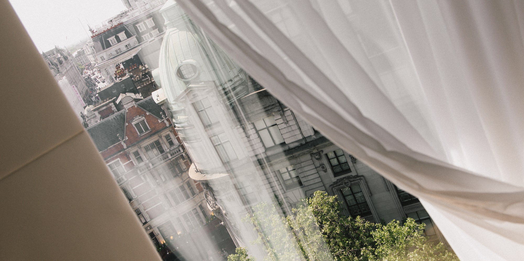 a window with a white curtain and a city view