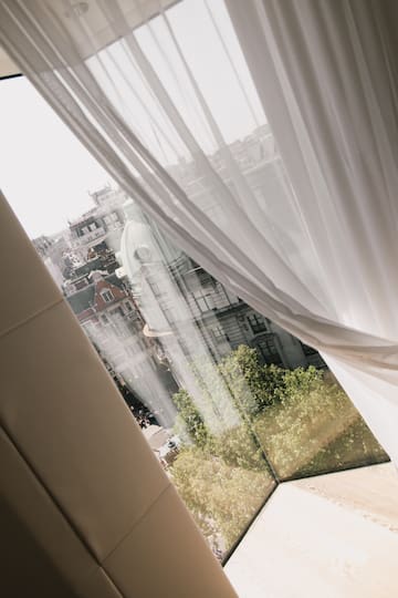 a window with a white curtain and a city view