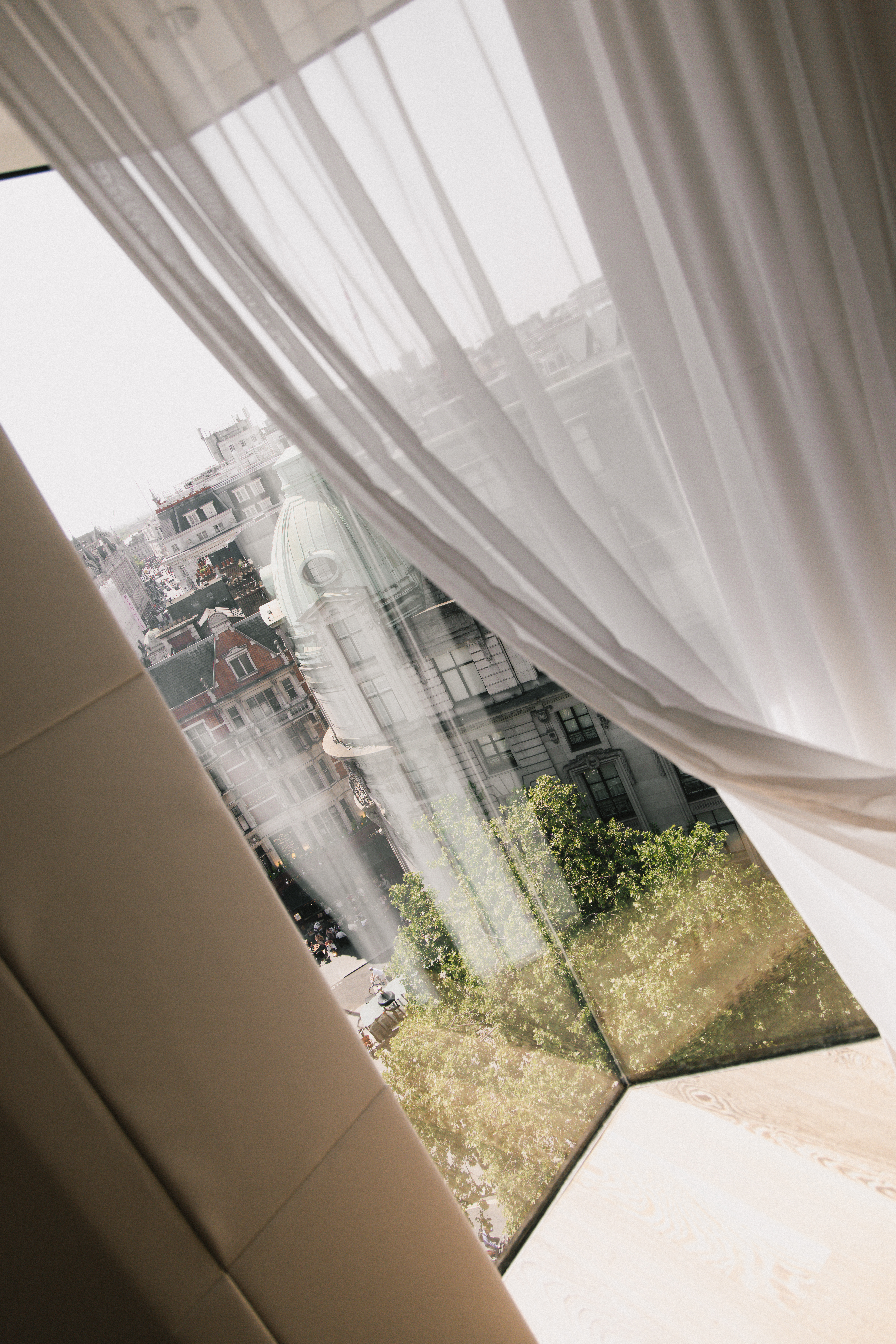 a window with a white curtain and a city view