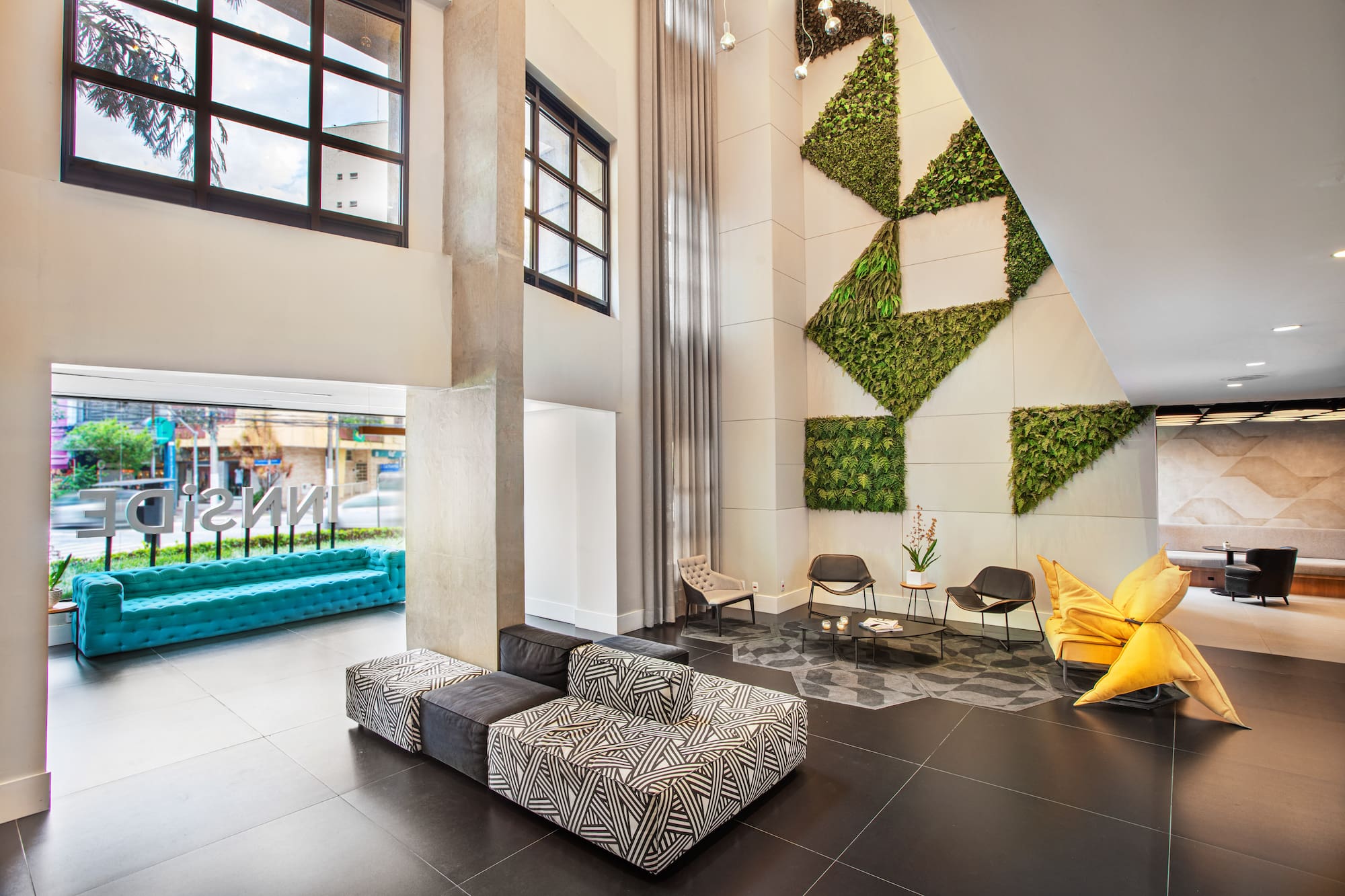 Modern hotel lobby with geometric green wall and varied stylish seating.