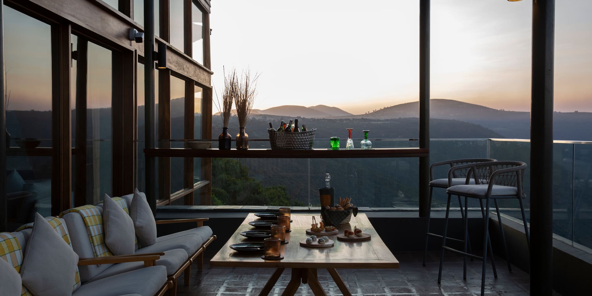 a table with drinks on it and a couch with a view of the mountains