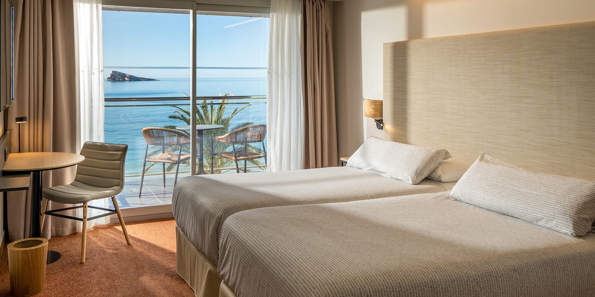 two beds in a room with a view of the ocean