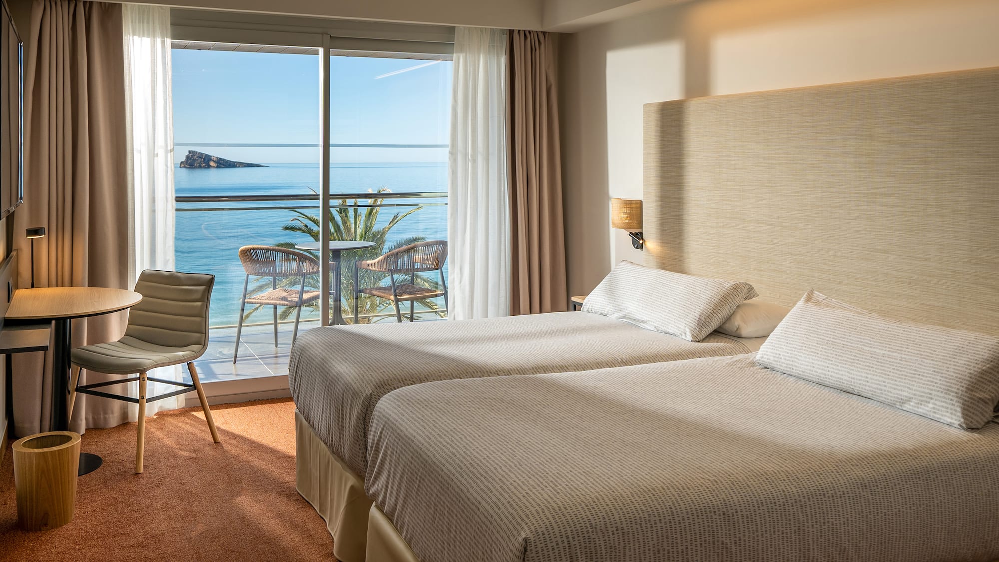 two beds in a room with a view of the ocean