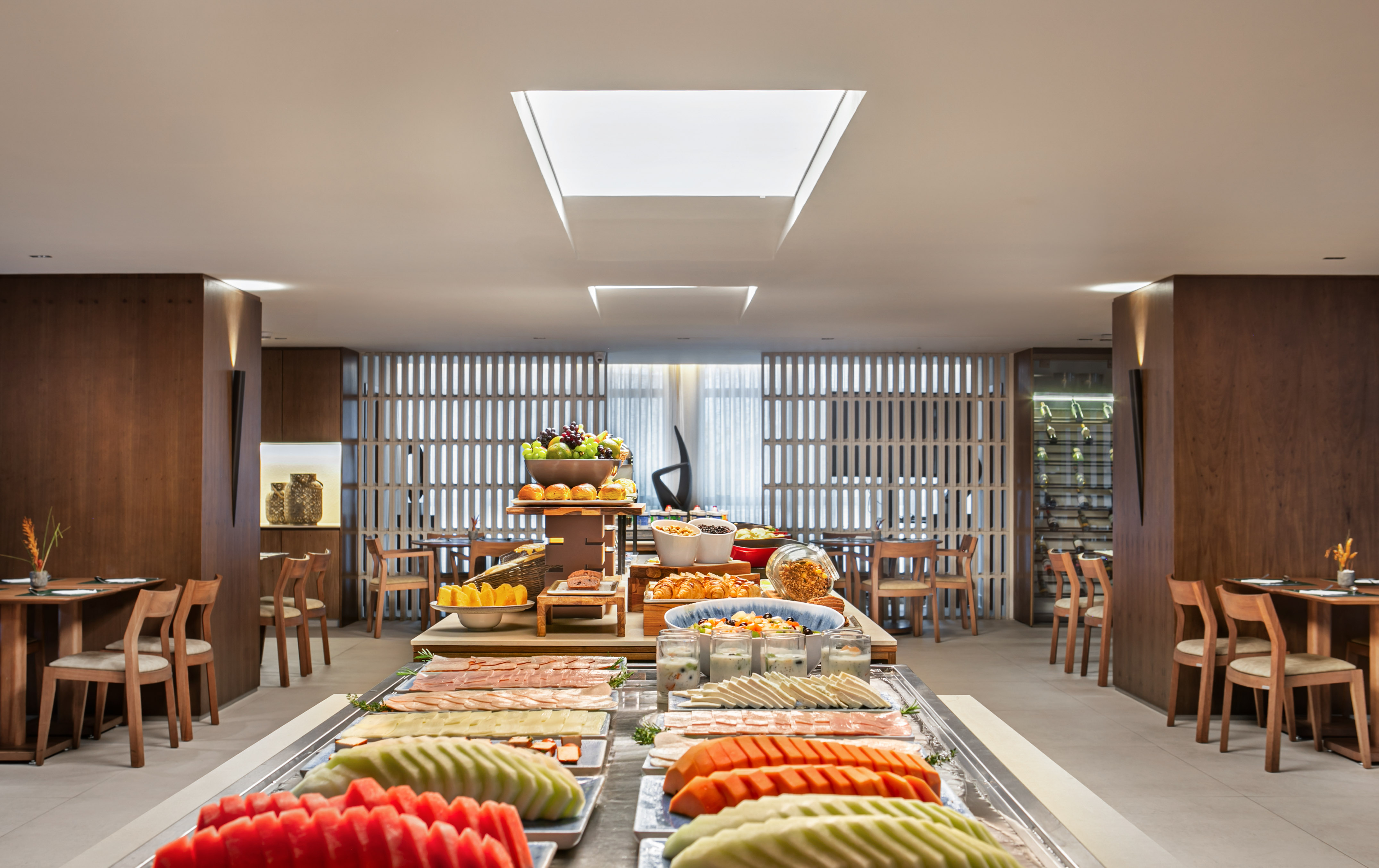 Hotel breakfast buffet with fresh fruit, cold cuts, pastries, and yogurt.