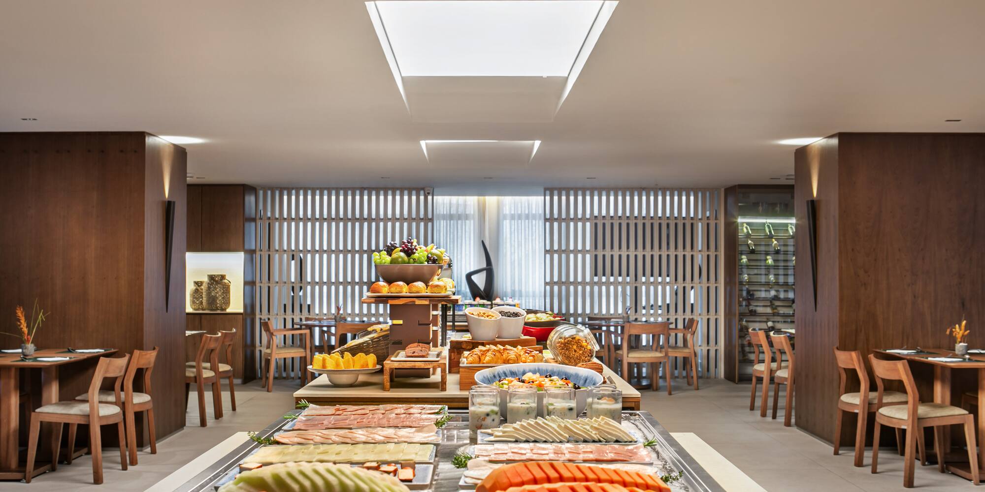 Hotel breakfast buffet with fresh fruit, cold cuts, pastries, and yogurt.
