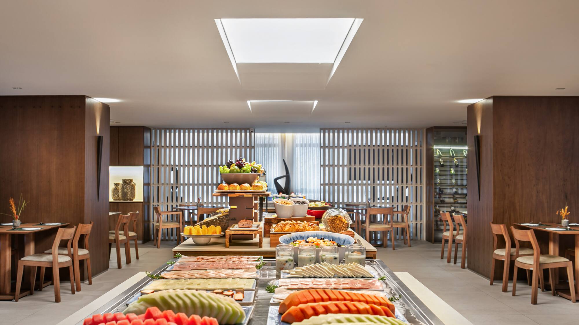 Hotel breakfast buffet with fresh fruit, cold cuts, pastries, and yogurt.