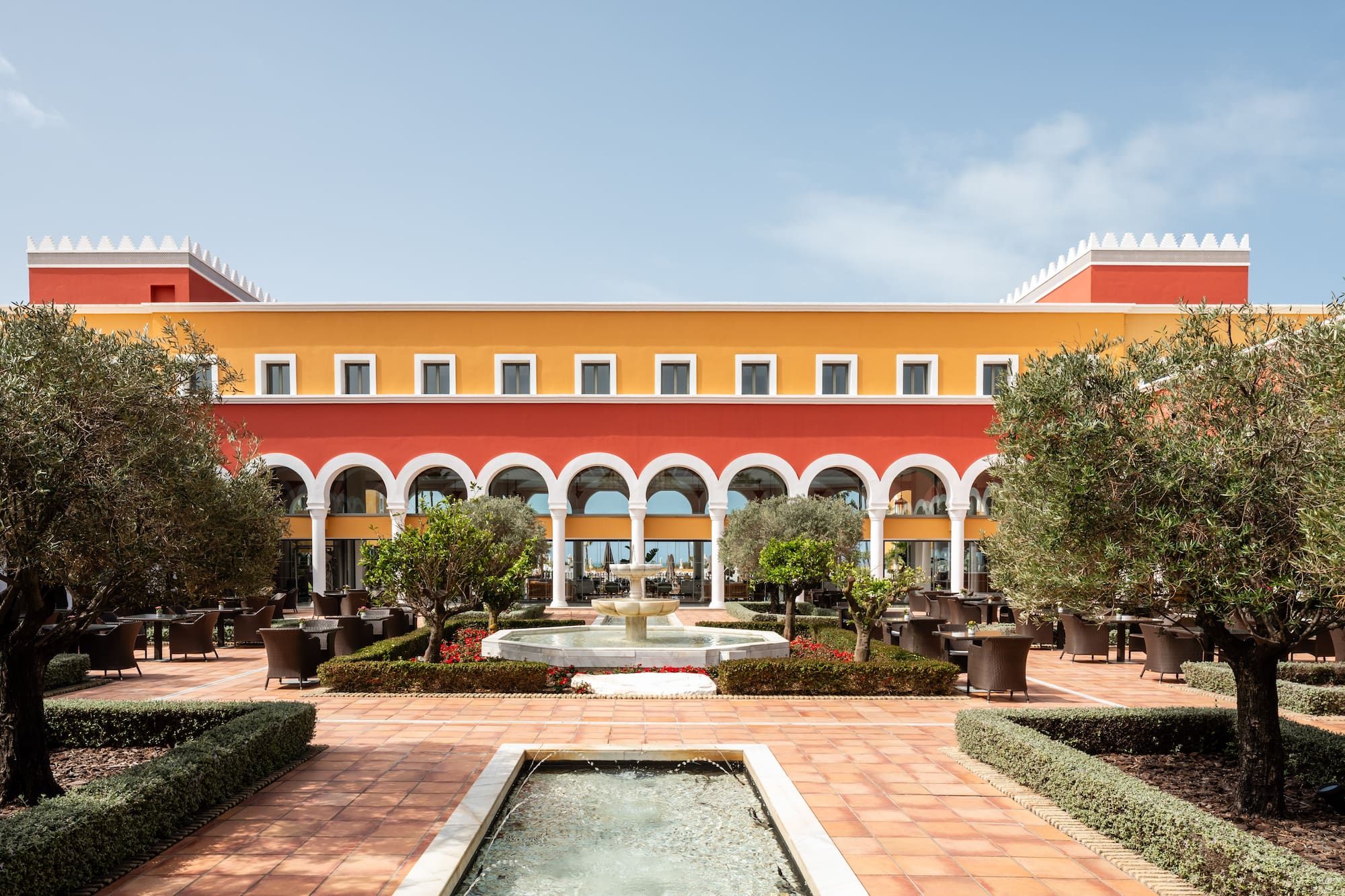 Colorful Mediterranean hotel courtyard with fountains and outdoor dining.