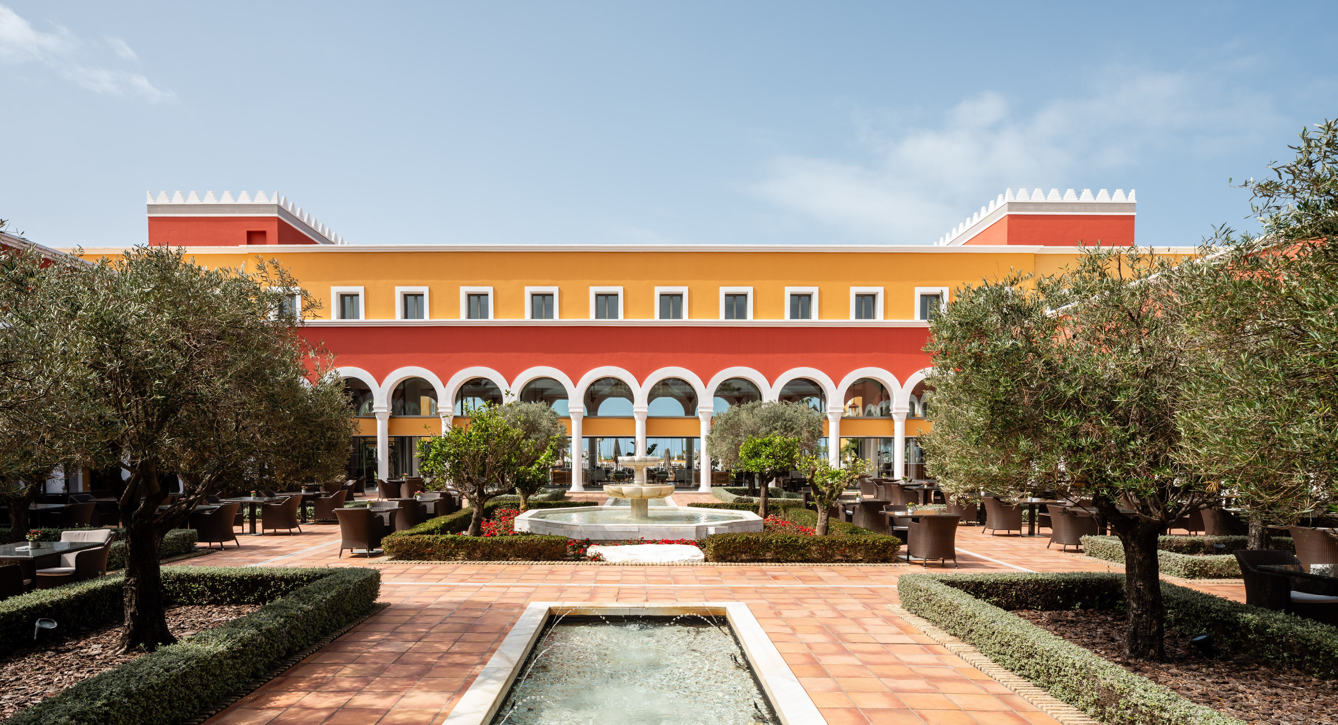 Colorful Mediterranean hotel courtyard with fountains and outdoor dining.