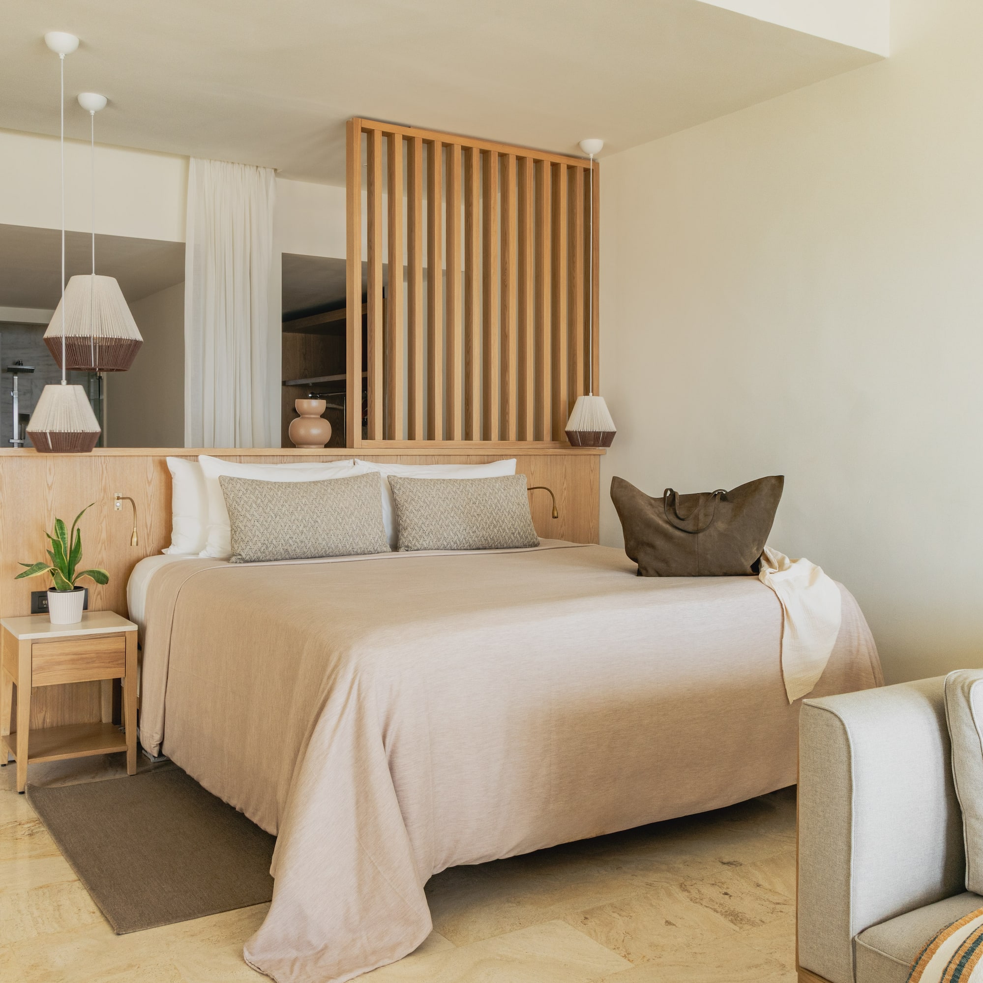 Modern hotel bedroom with neutral decor, wooden headboard, and large bed.