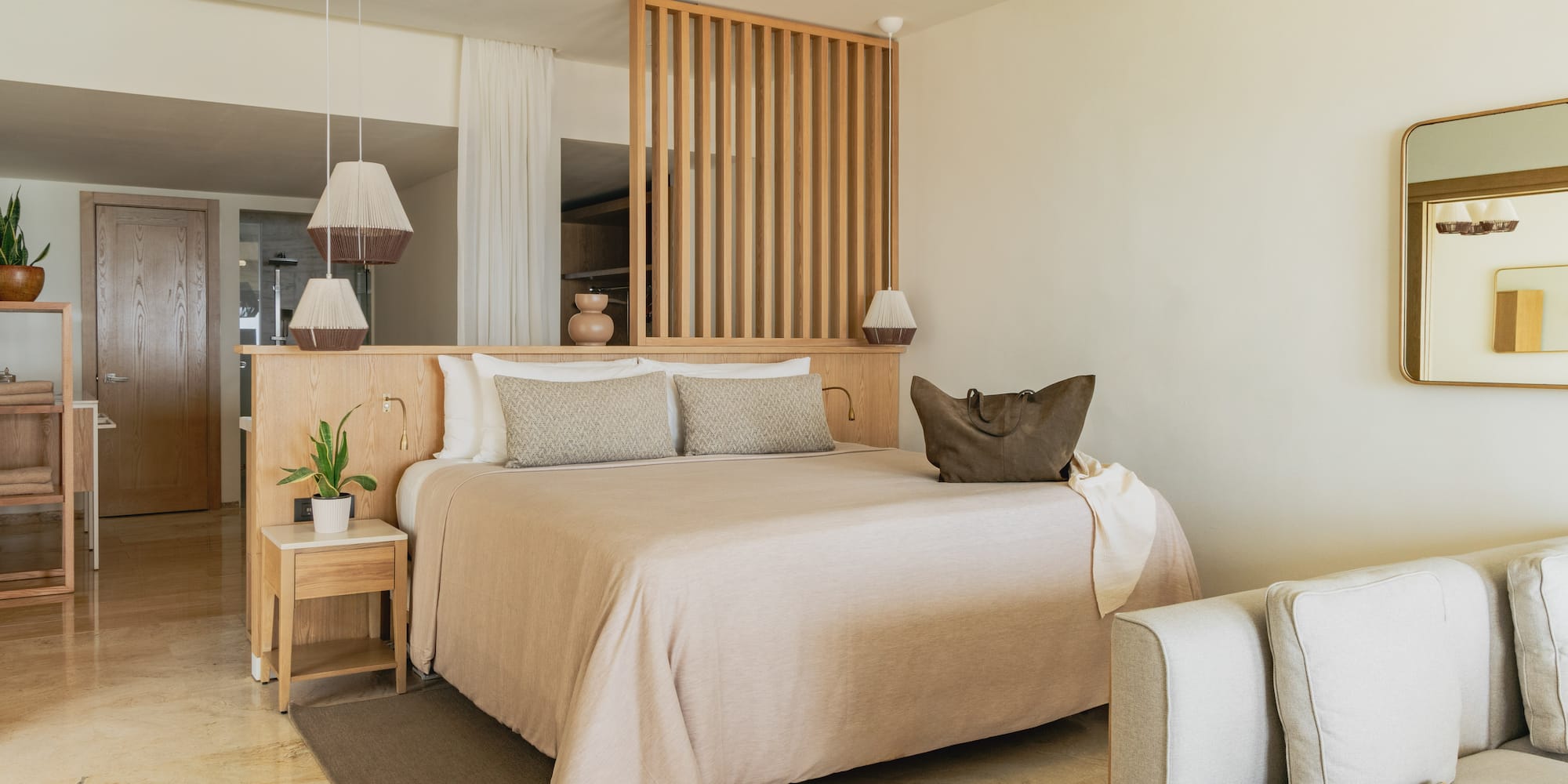 Modern hotel bedroom with neutral decor, wooden headboard, and large bed.