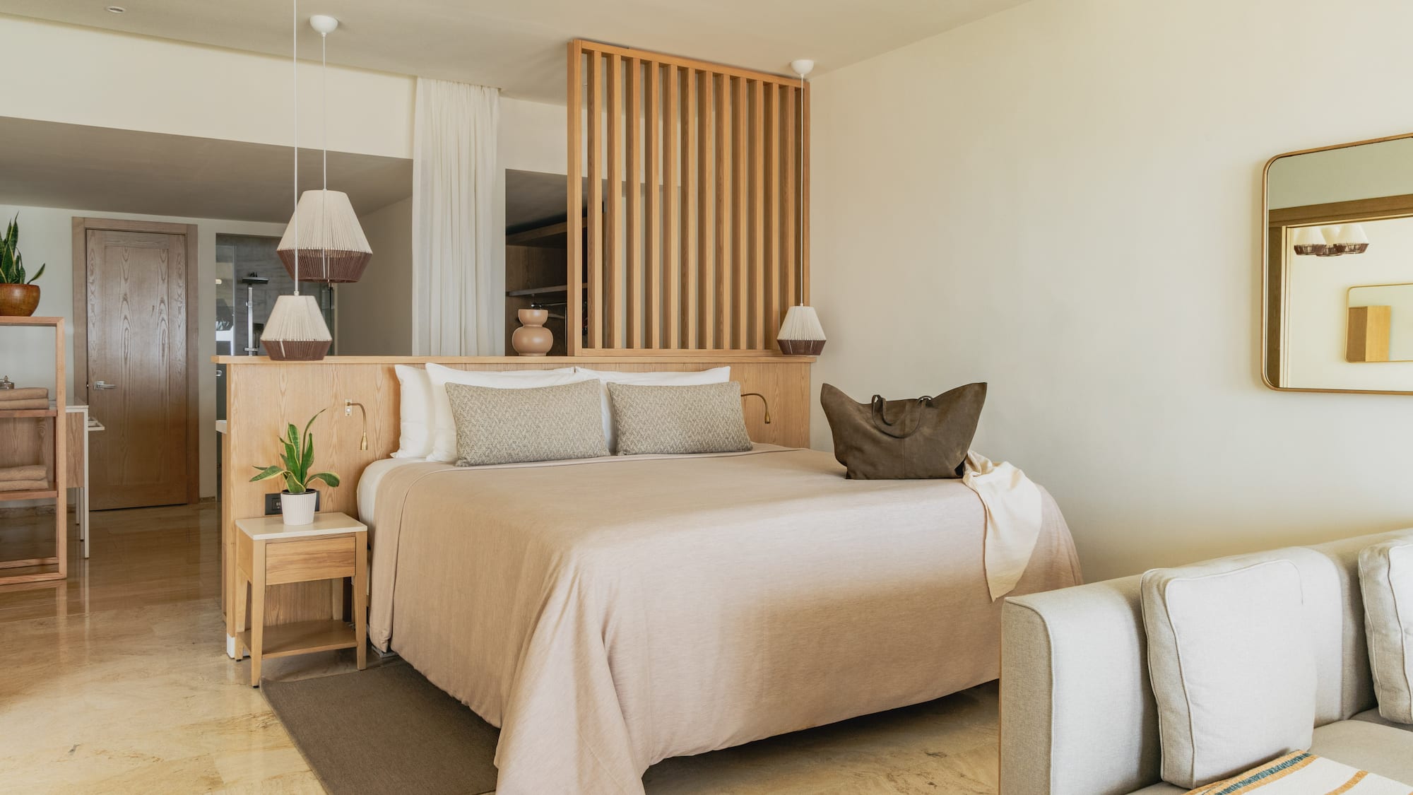 Modern hotel bedroom with neutral decor, wooden headboard, and large bed.