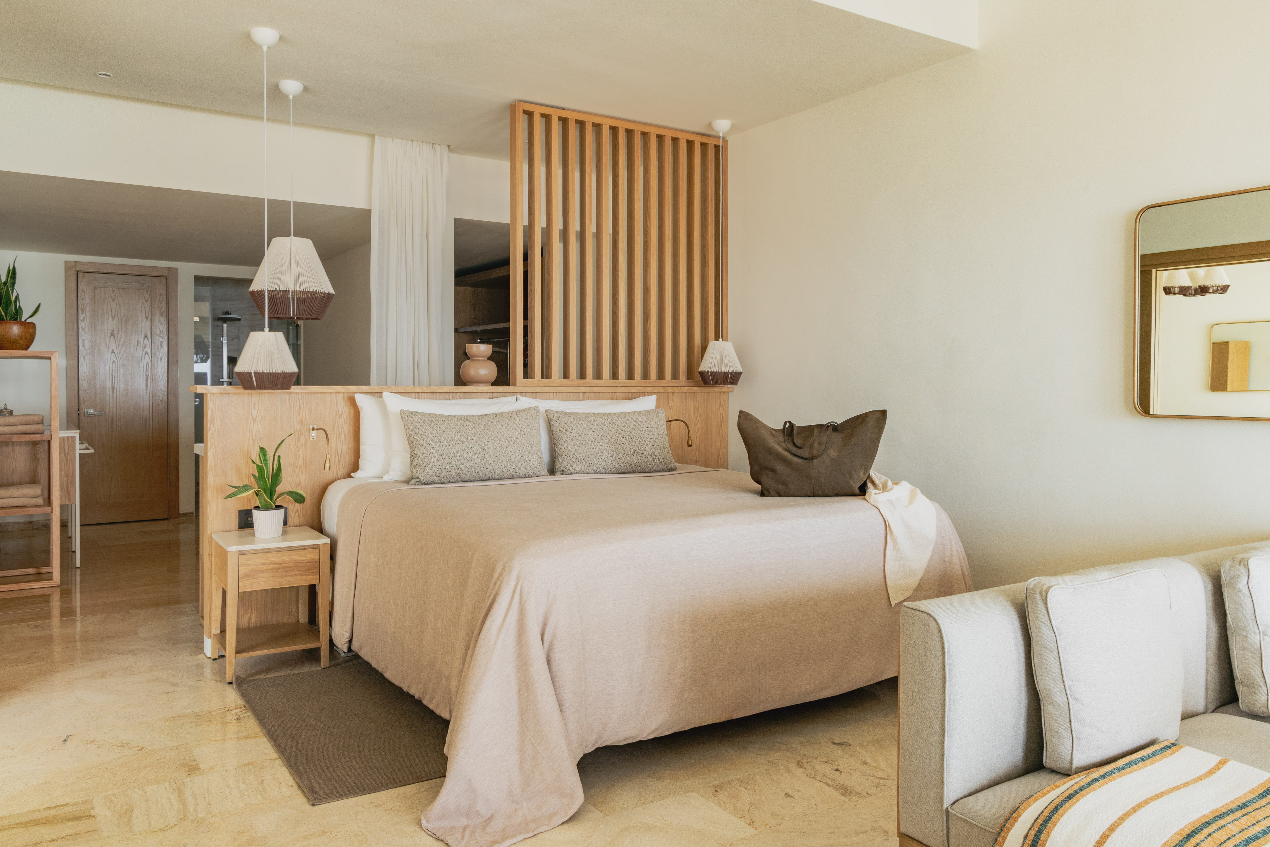 Modern hotel bedroom with neutral decor, wooden headboard, and large bed.