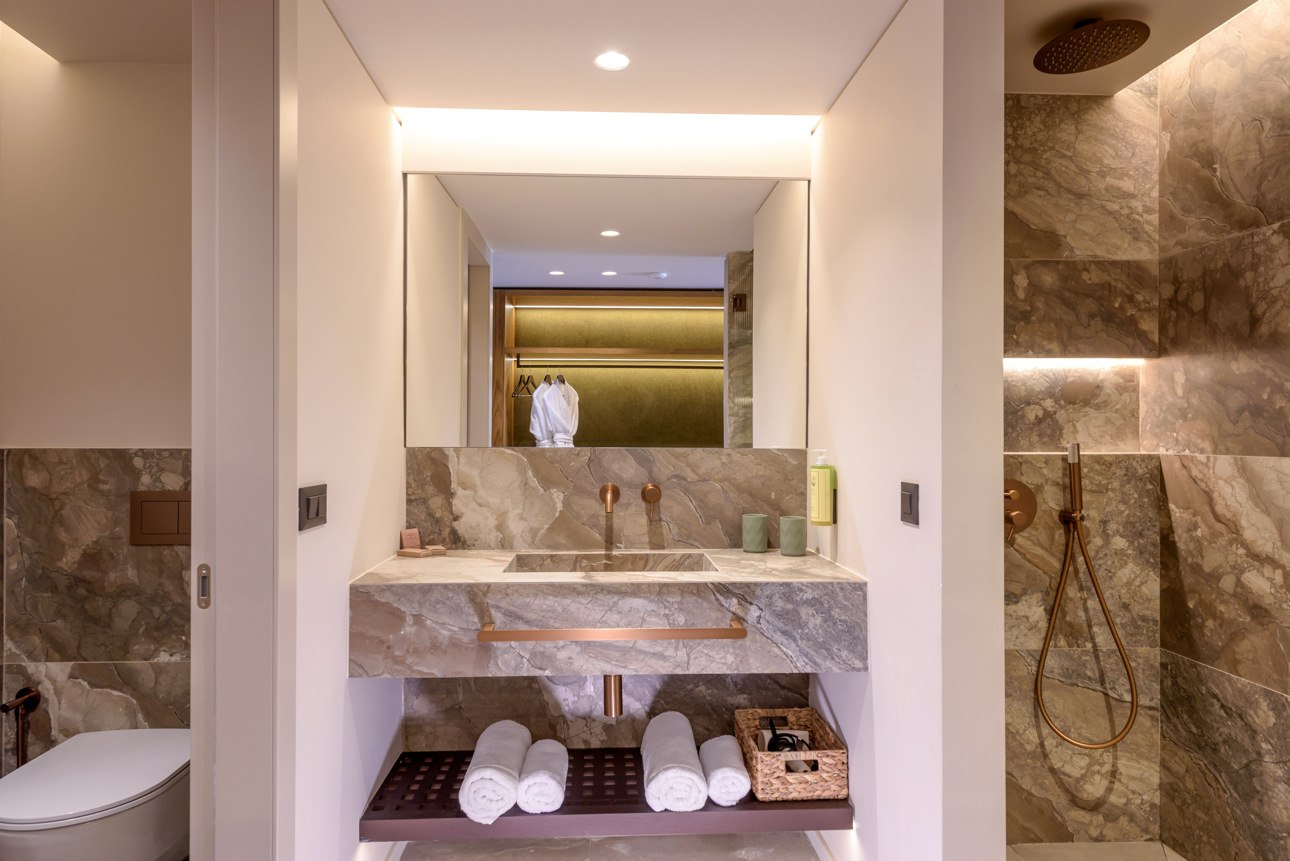 Luxury marble hotel bathroom with copper fixtures and modern shower.