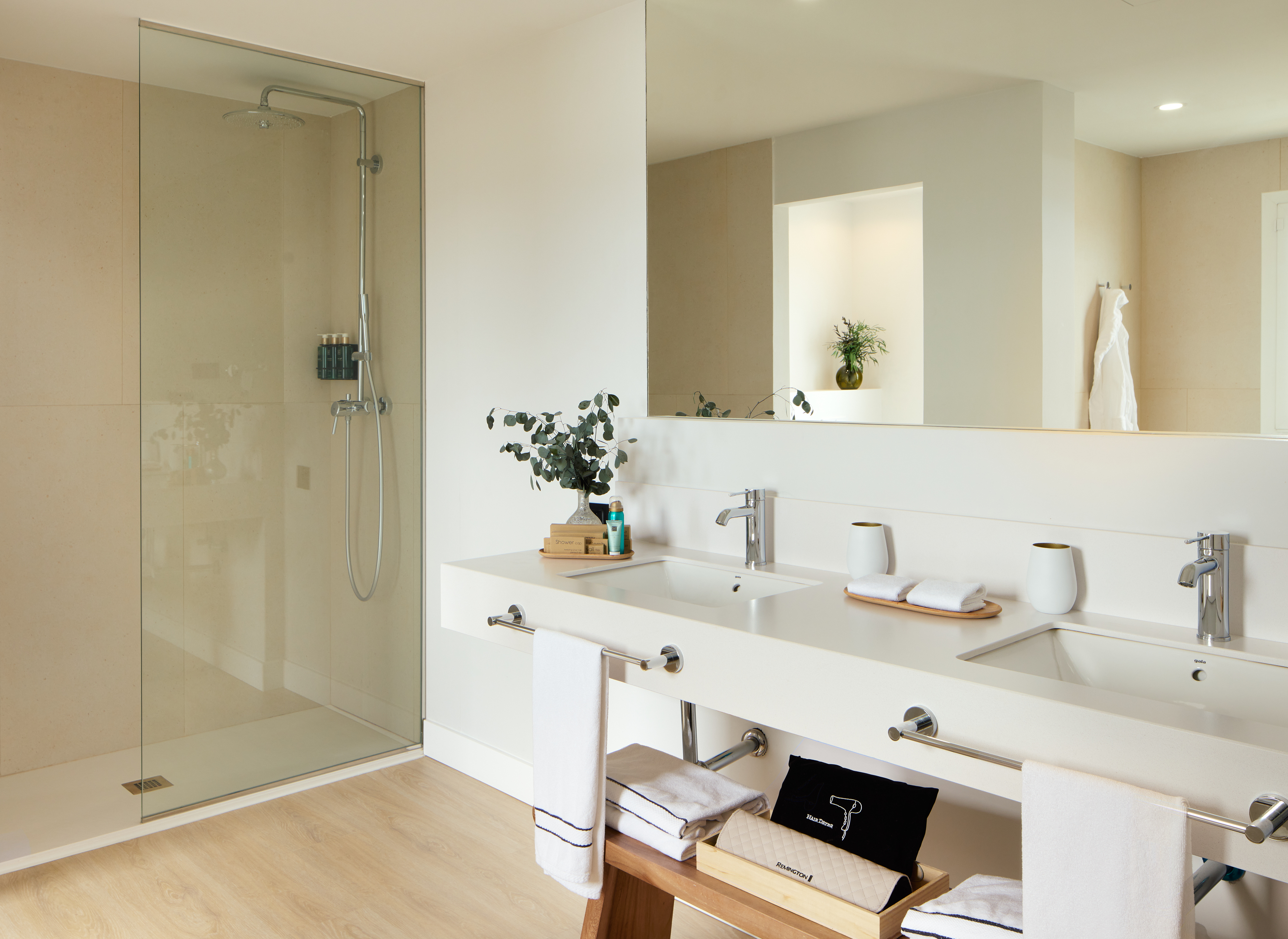 Bright modern bathroom with walk-in glass shower, double sinks, and large mirror.