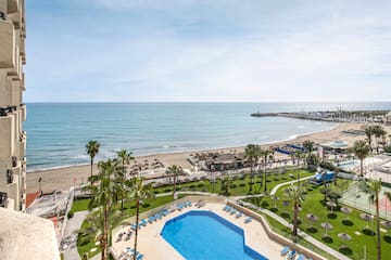 a pool and beach with palm trees and a pier