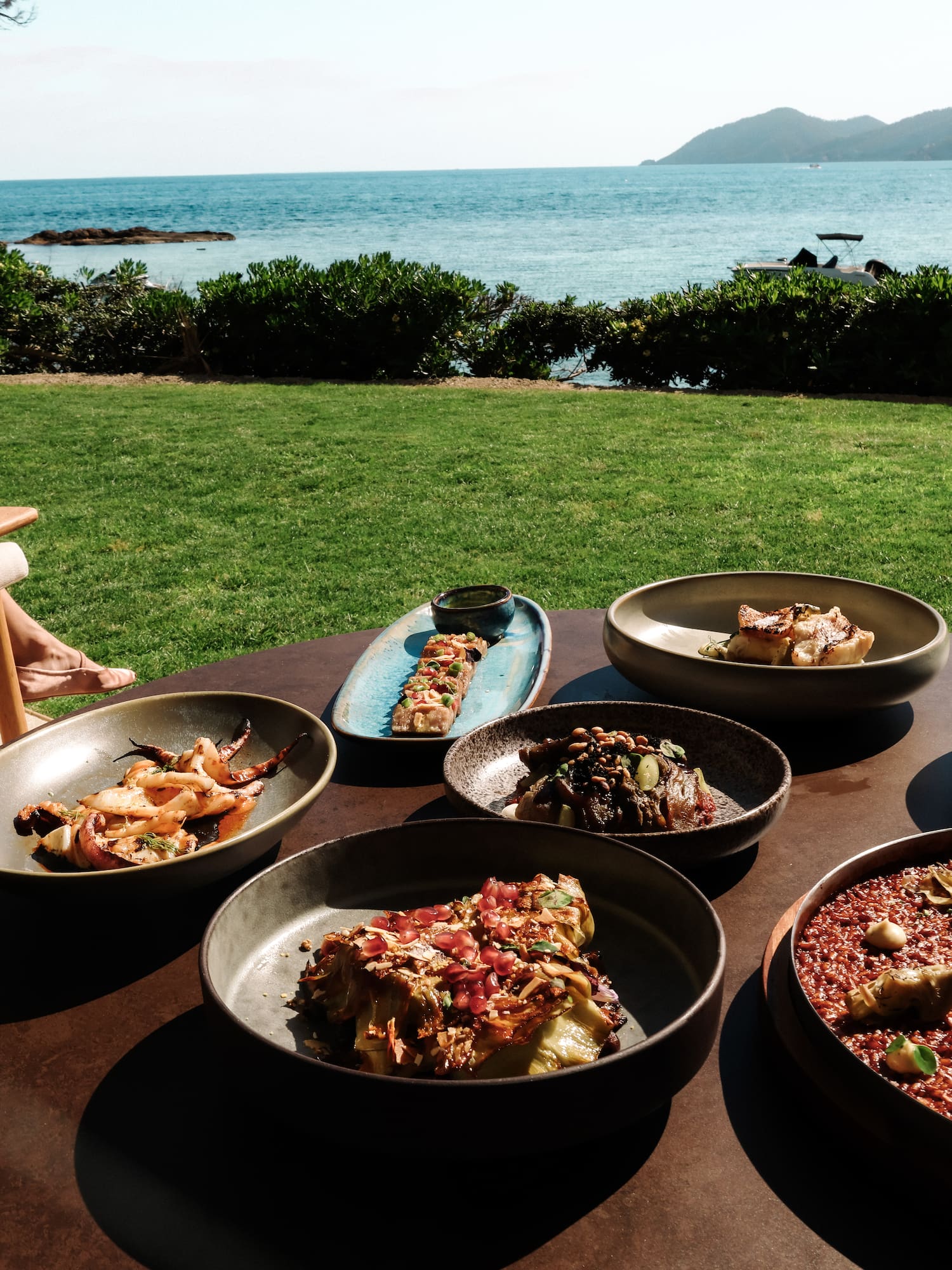 Al fresco meal: seafood, paella, small plates, ocean view, person reading.