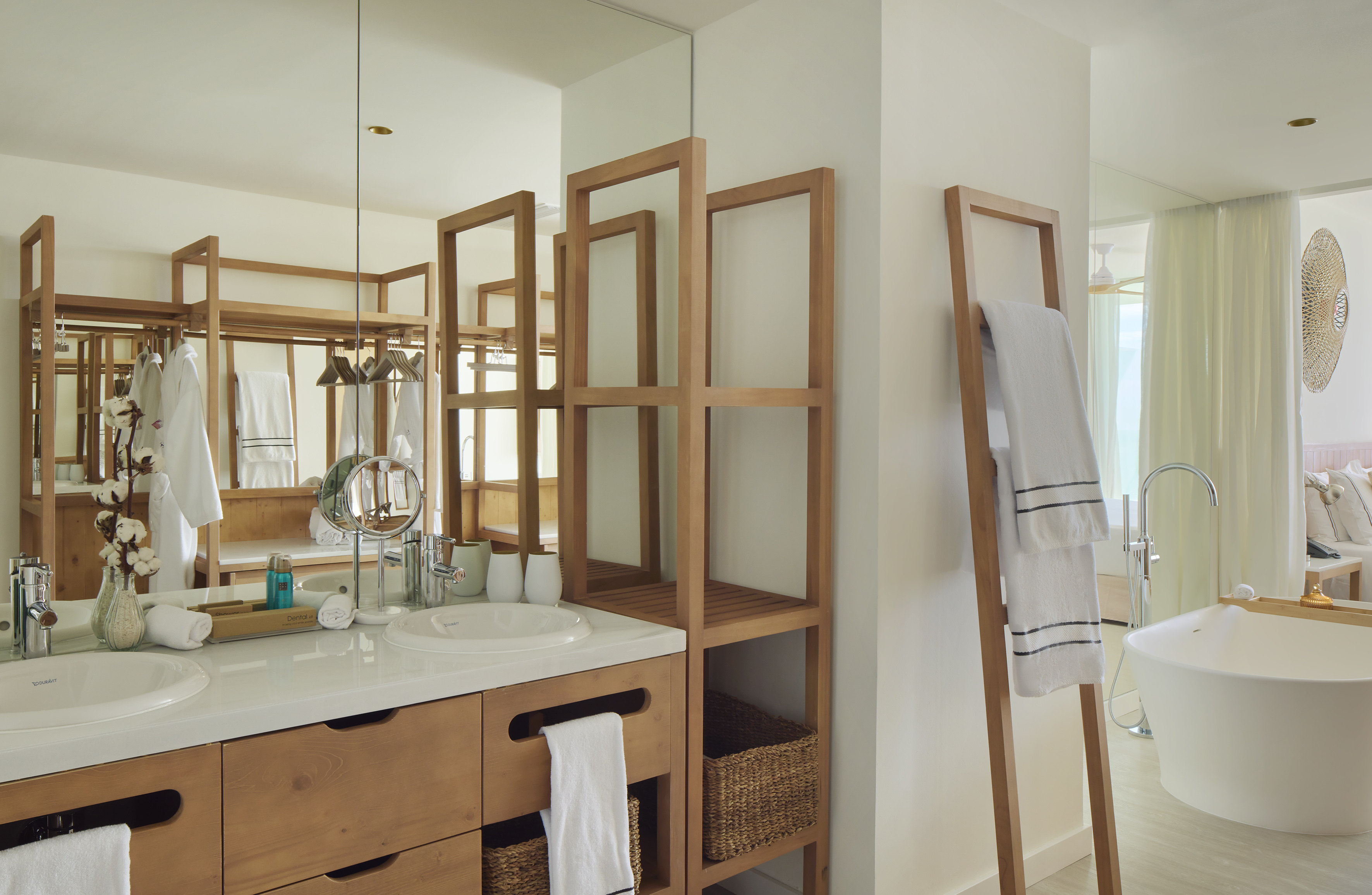 Modern hotel bathroom with wood double vanity, mirrors, freestanding tub.
