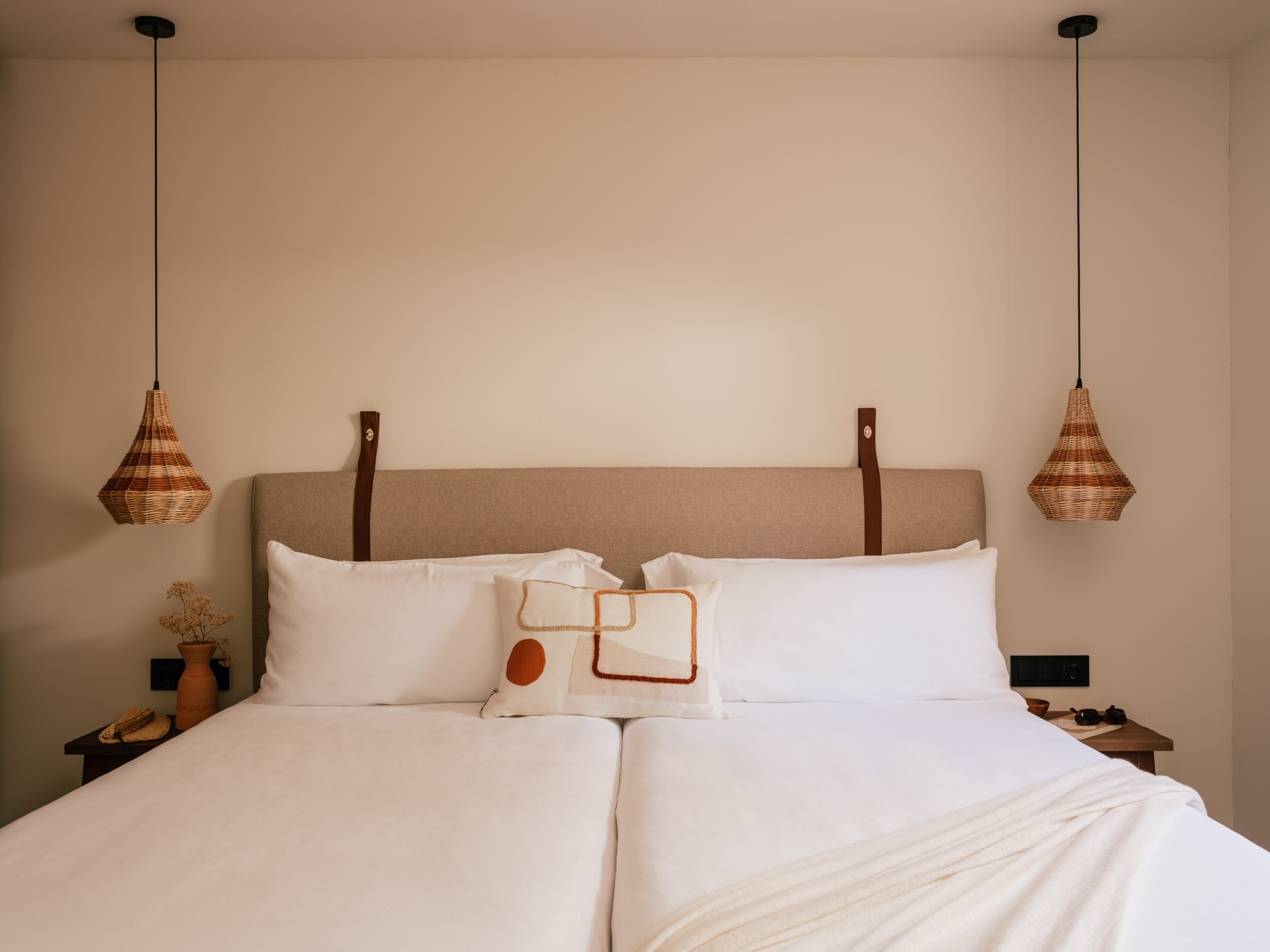 Modern bedroom with neutral decor, white bed, and wicker pendant lights.