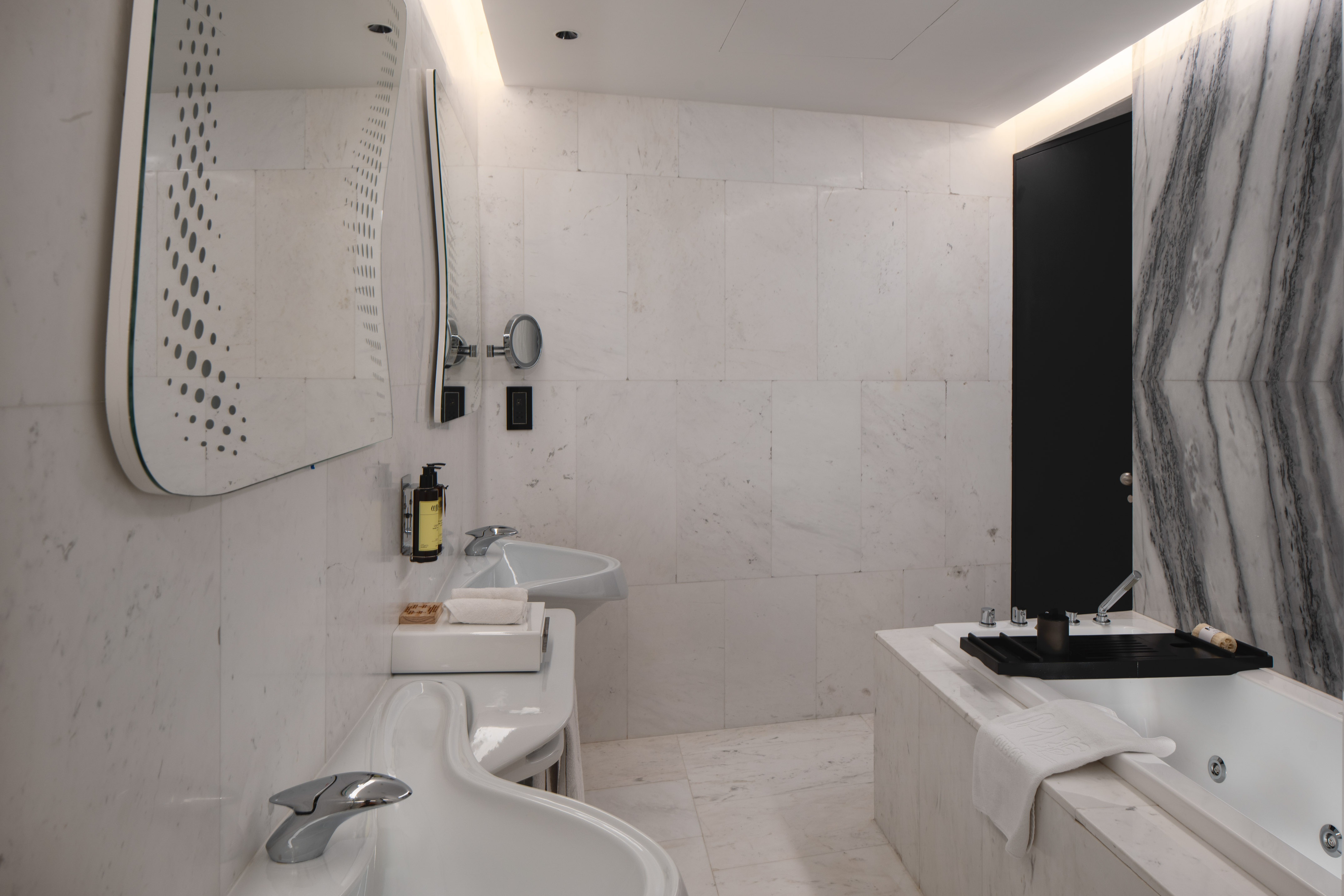 Modern luxury bathroom with white marble, double vanity, and contemporary bathtub.