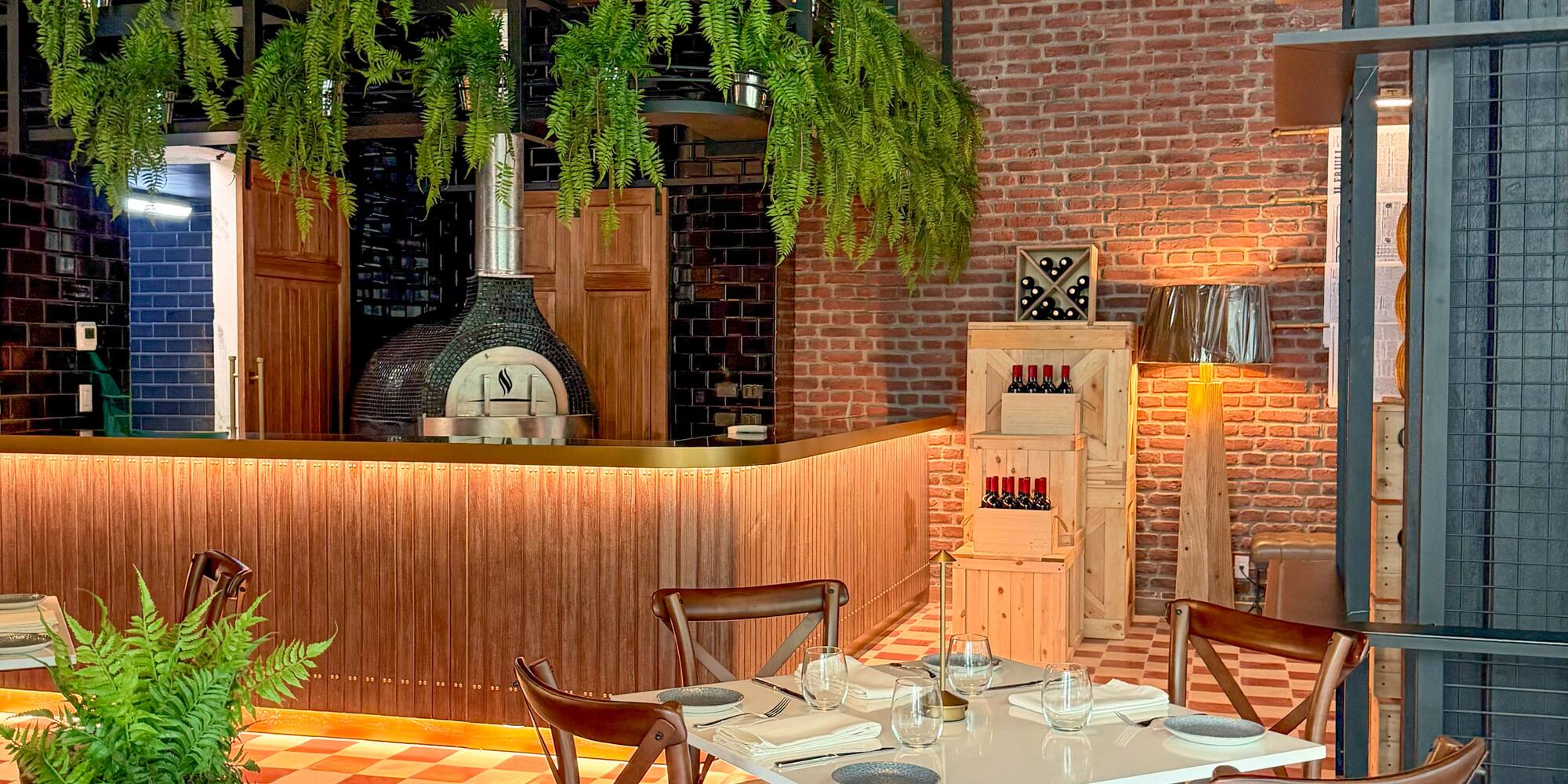 Restaurant with pizza oven, dining table, brick wall, and red checkered floor.