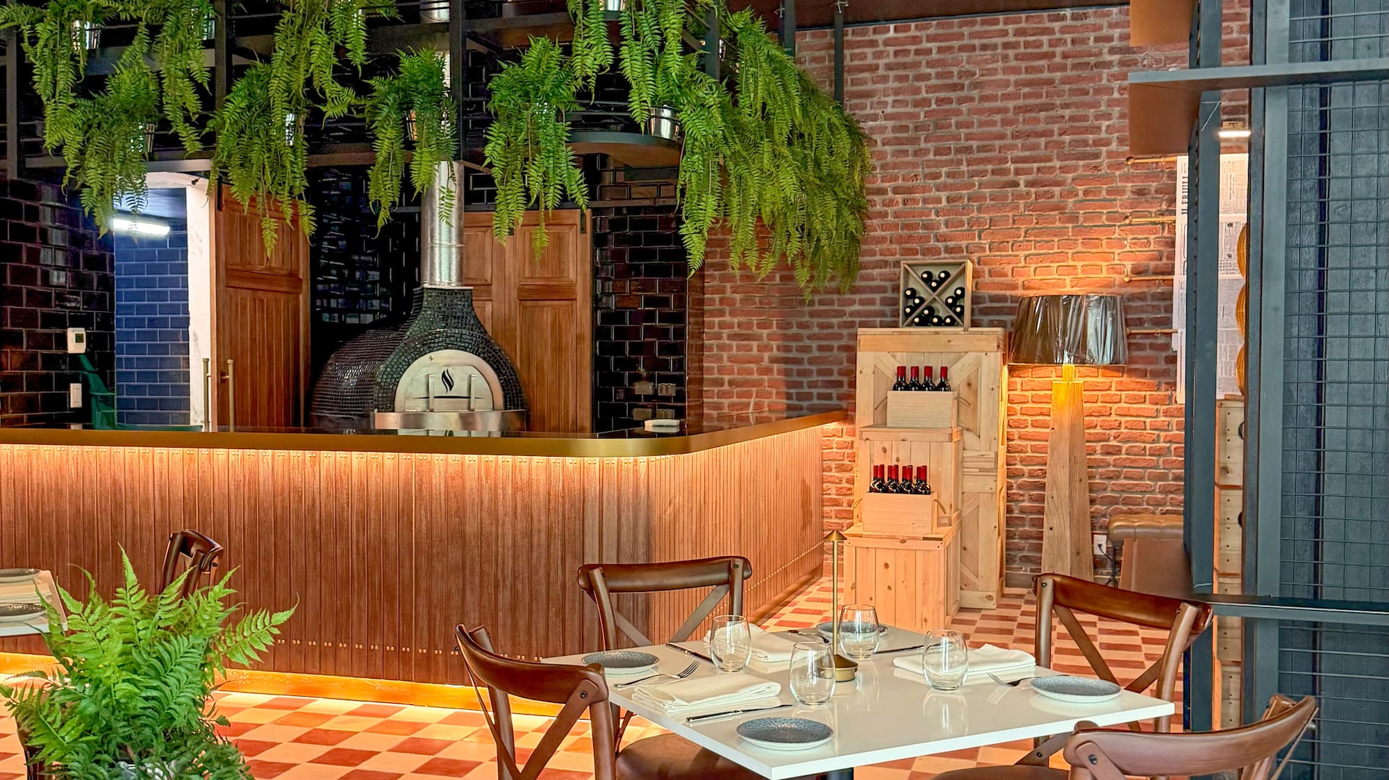 Restaurant with pizza oven, dining table, brick wall, and red checkered floor.