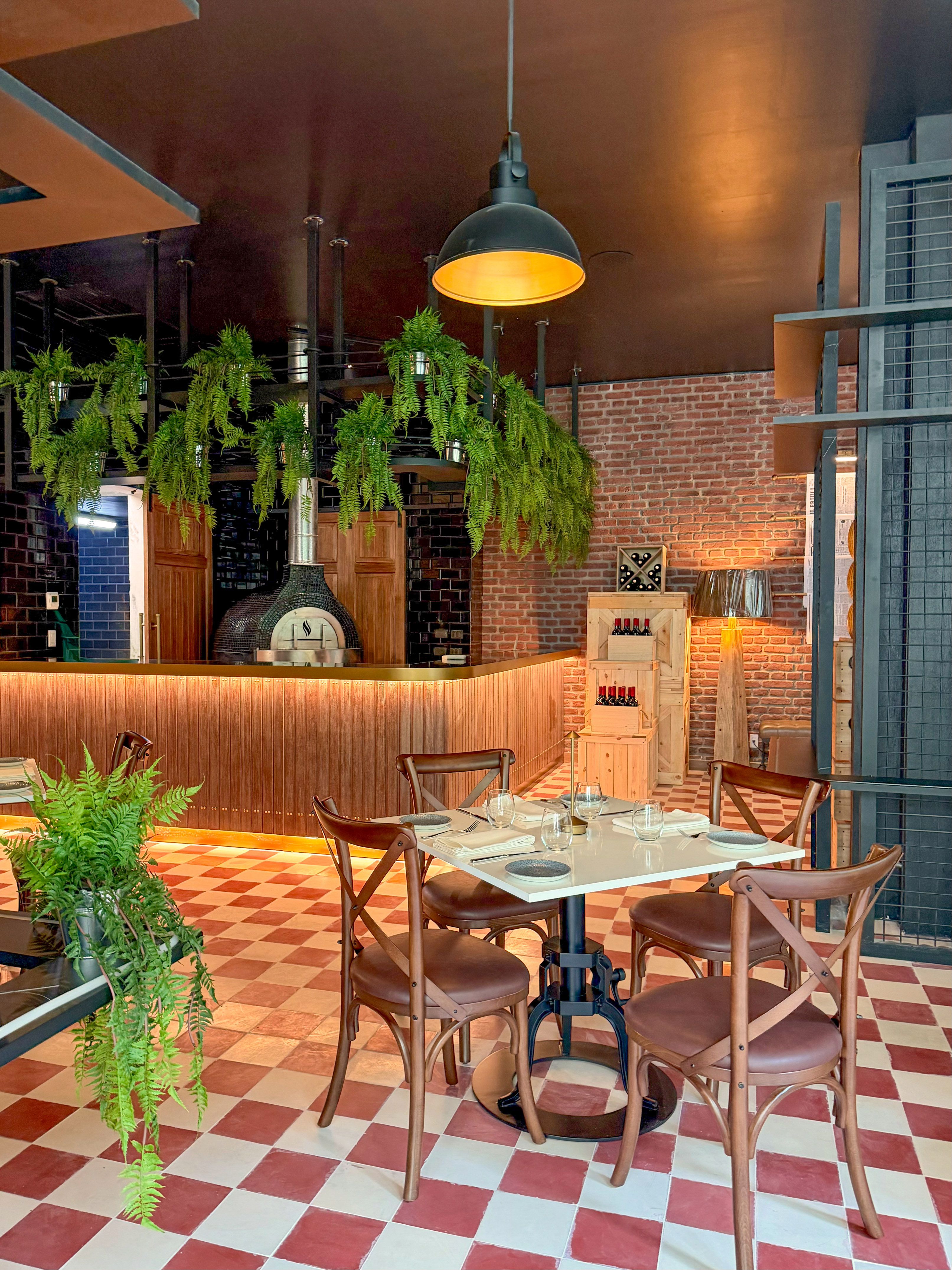 Restaurant with pizza oven, dining table, brick wall, and red checkered floor.