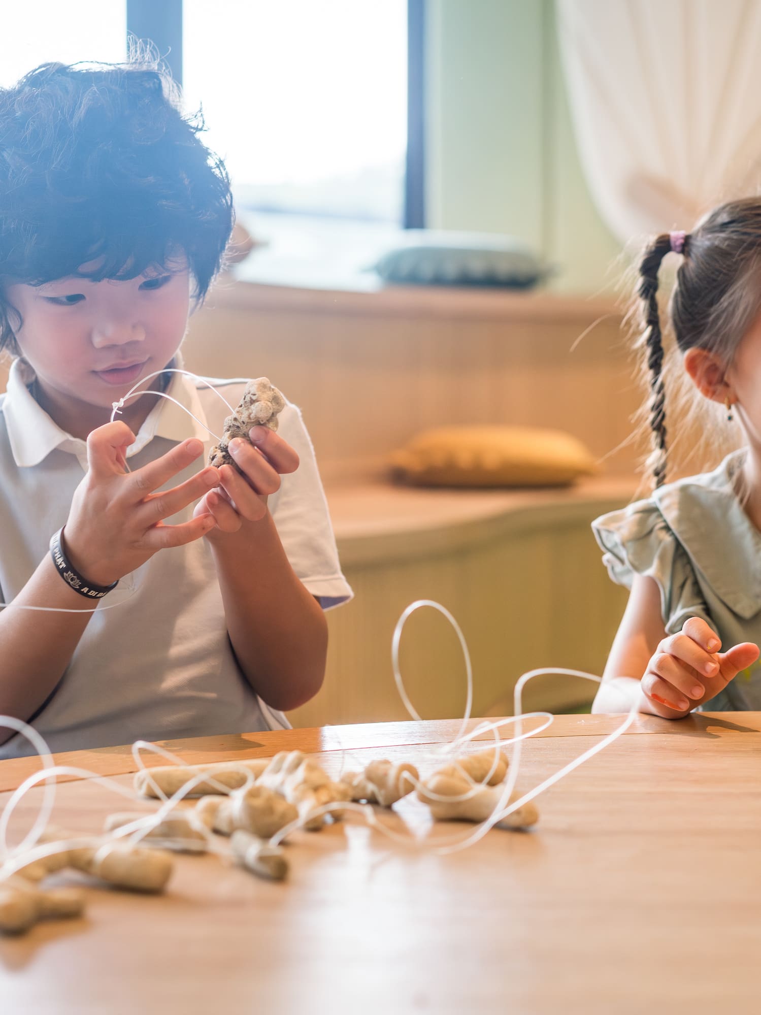 Niño y niña haciendo manualidades con materiales naturales en mesa.