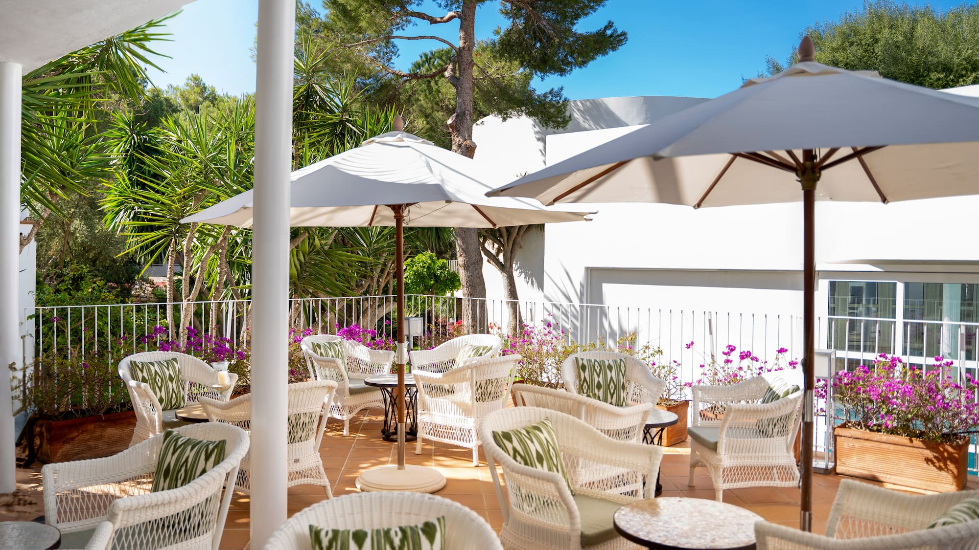 a patio with white chairs and umbrellas