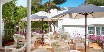 a patio with white chairs and umbrellas