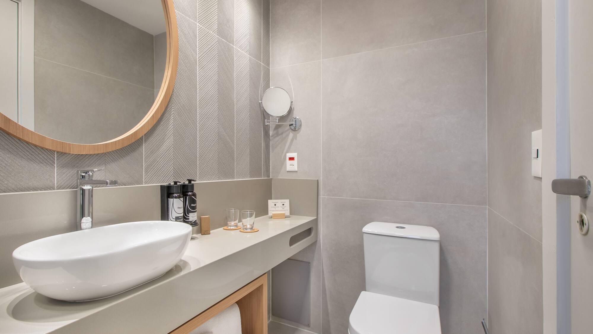 a bathroom with a round mirror and sink