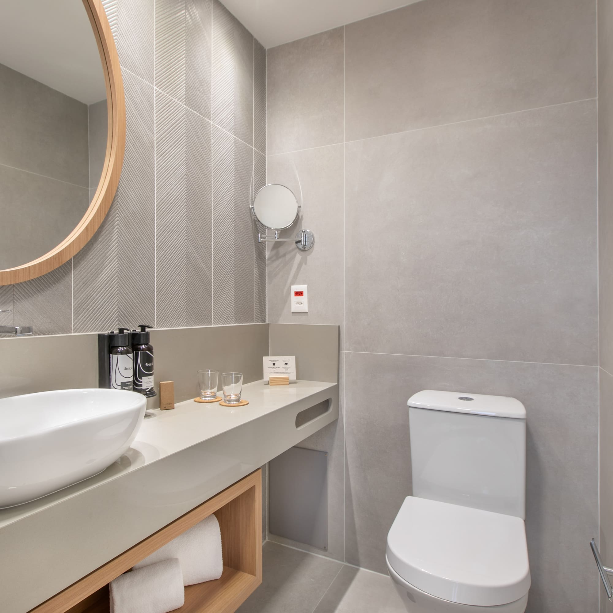a bathroom with a round mirror and sink