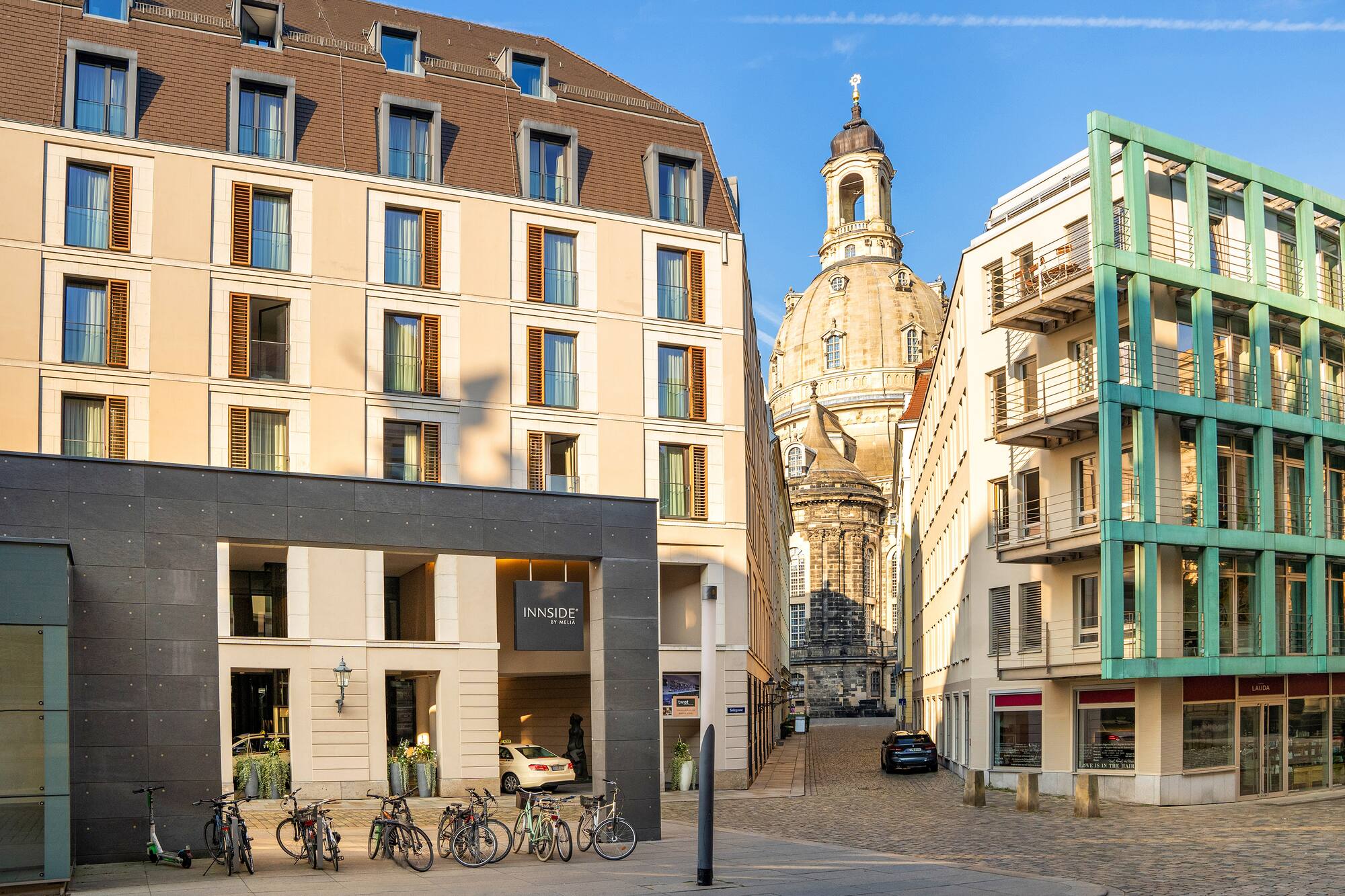 Sunny Dresden street with INNSiDE by Meliá hotel, Frauenkirche dome, bikes