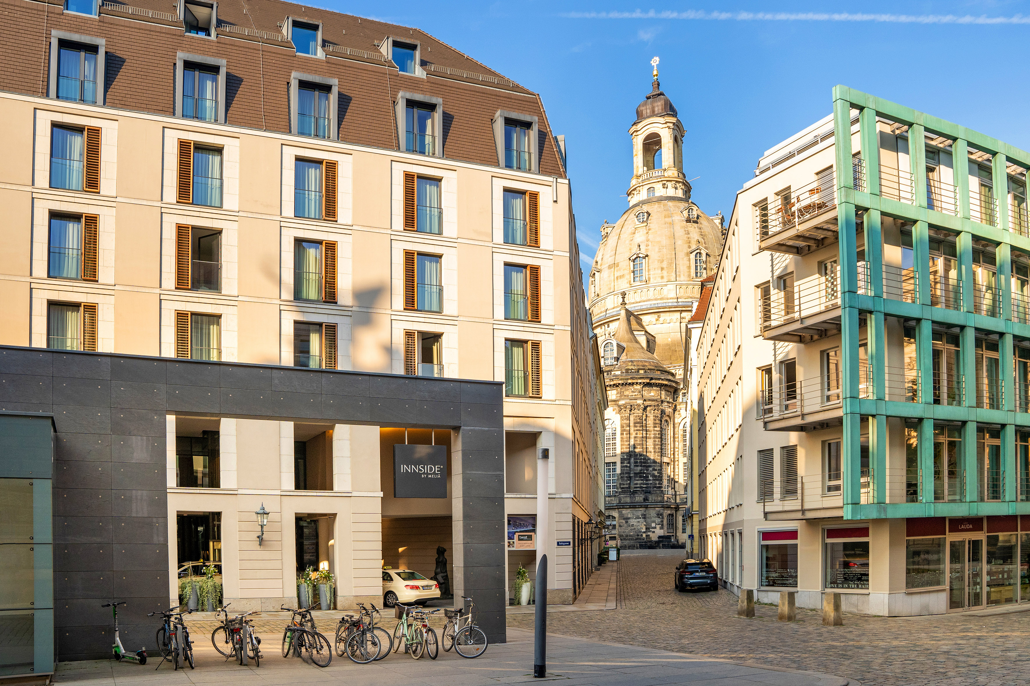 Sunny Dresden street with INNSiDE by Meliá hotel, Frauenkirche dome, bikes