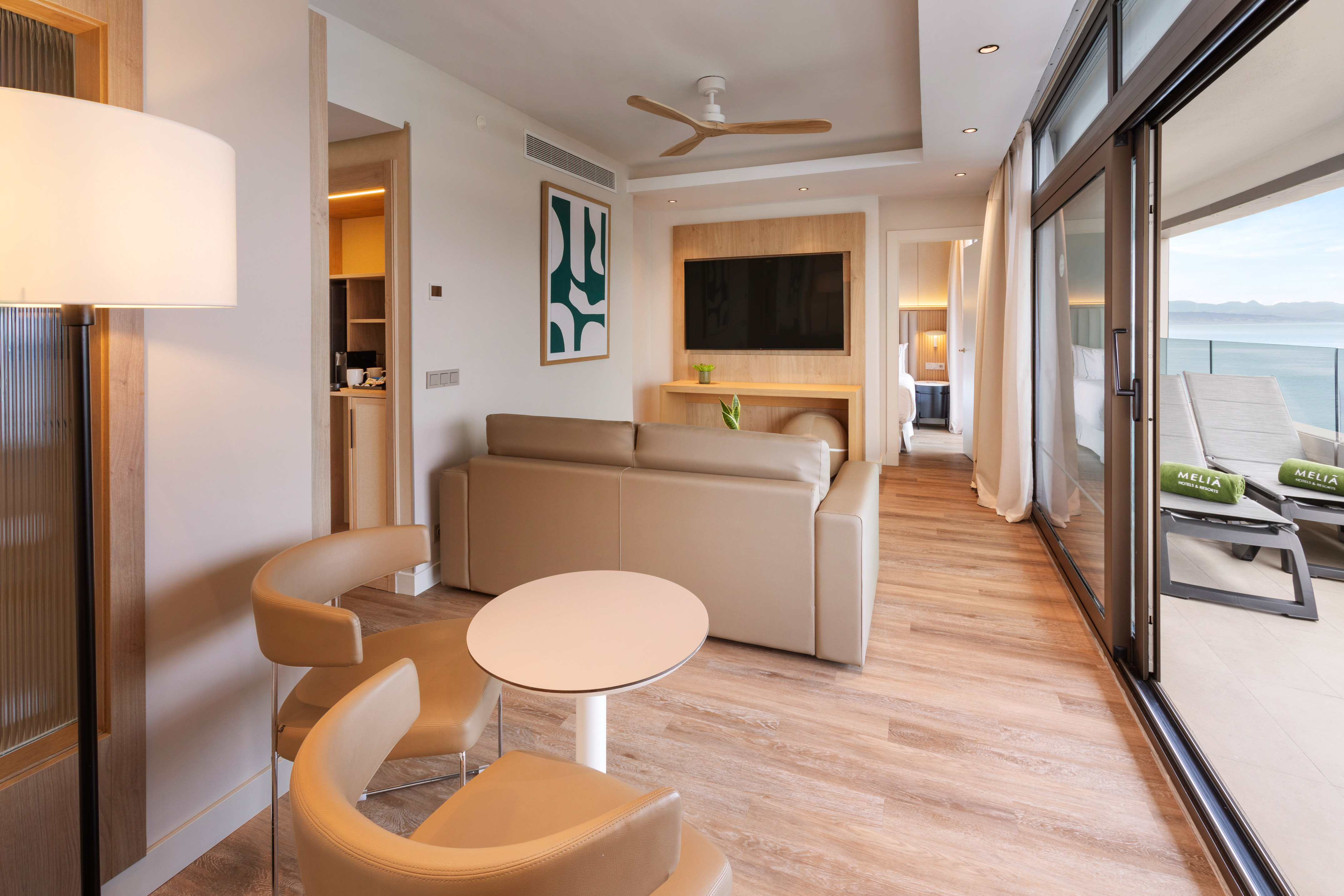 Melia hotel suite living area with sea view balcony and beige sofa.