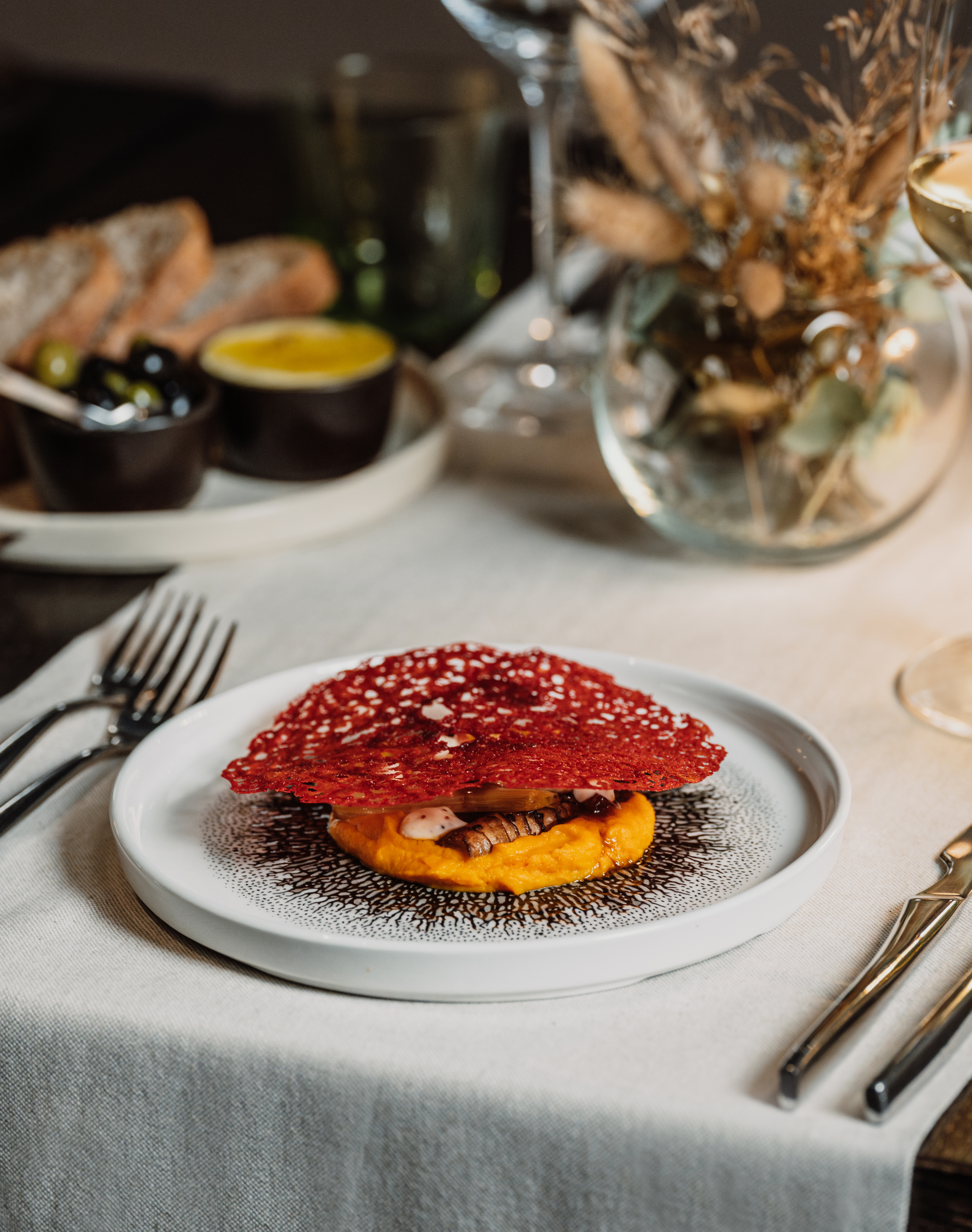 Gourmet plated dish: orange purée, mushrooms, red tuile. Elegant restaurant meal.