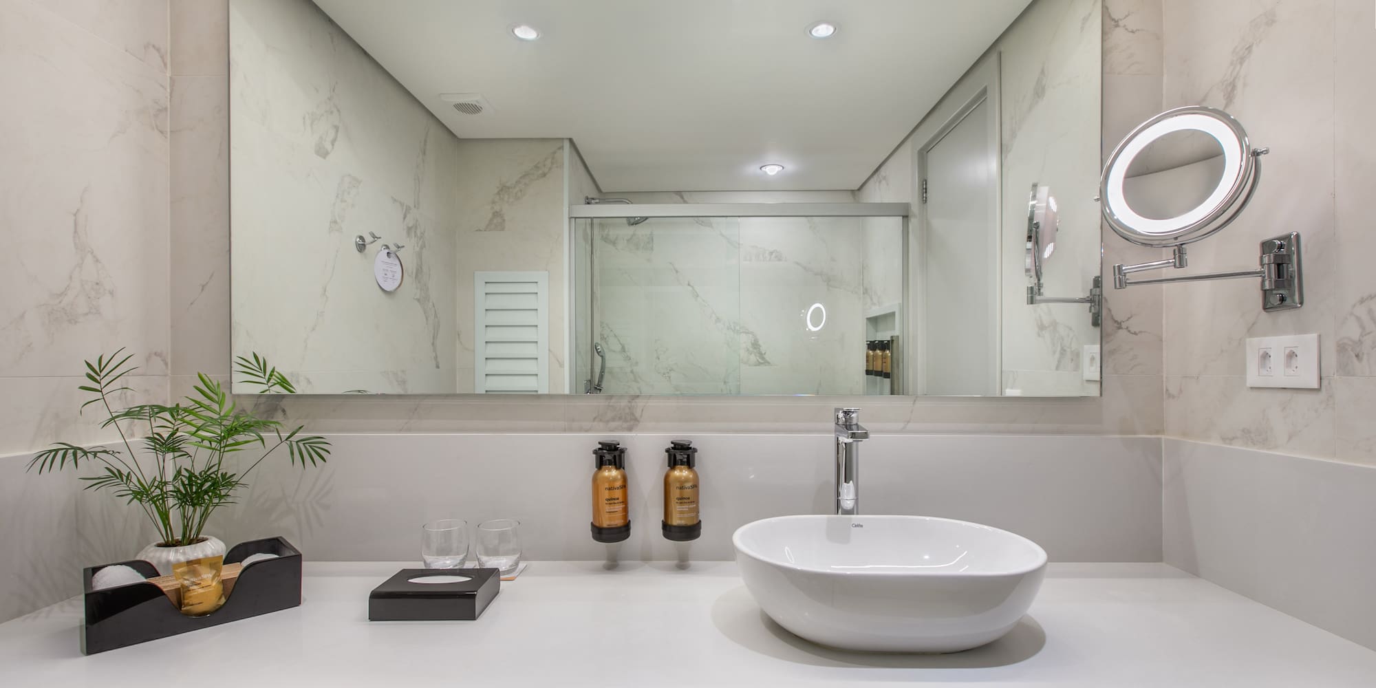Modern hotel bathroom with white vanity, vessel sink, and large mirror.